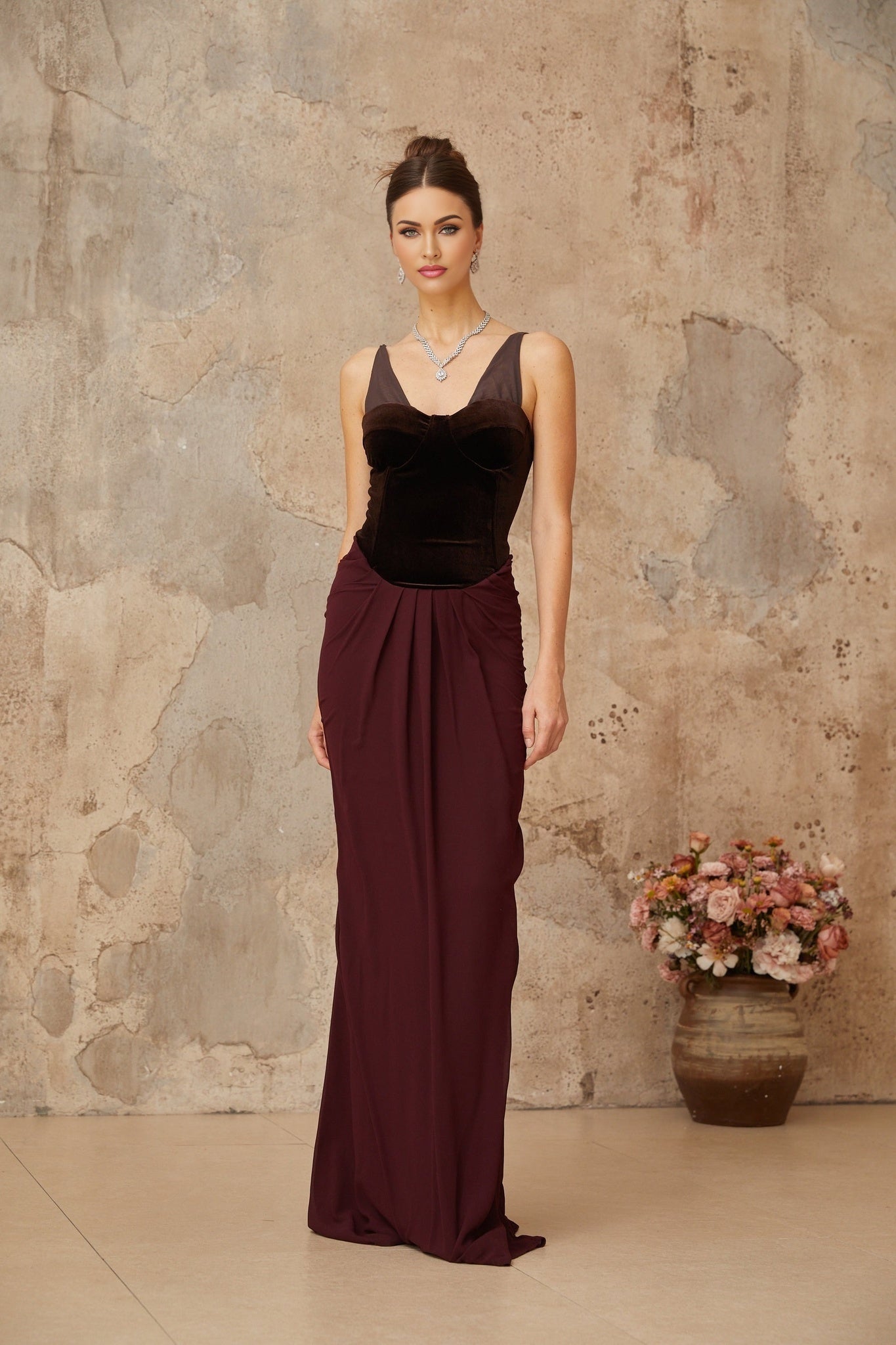 A long burgundy maxi dress with velvet panels and shirred detailing featuring a flowing silhouette and deep red color