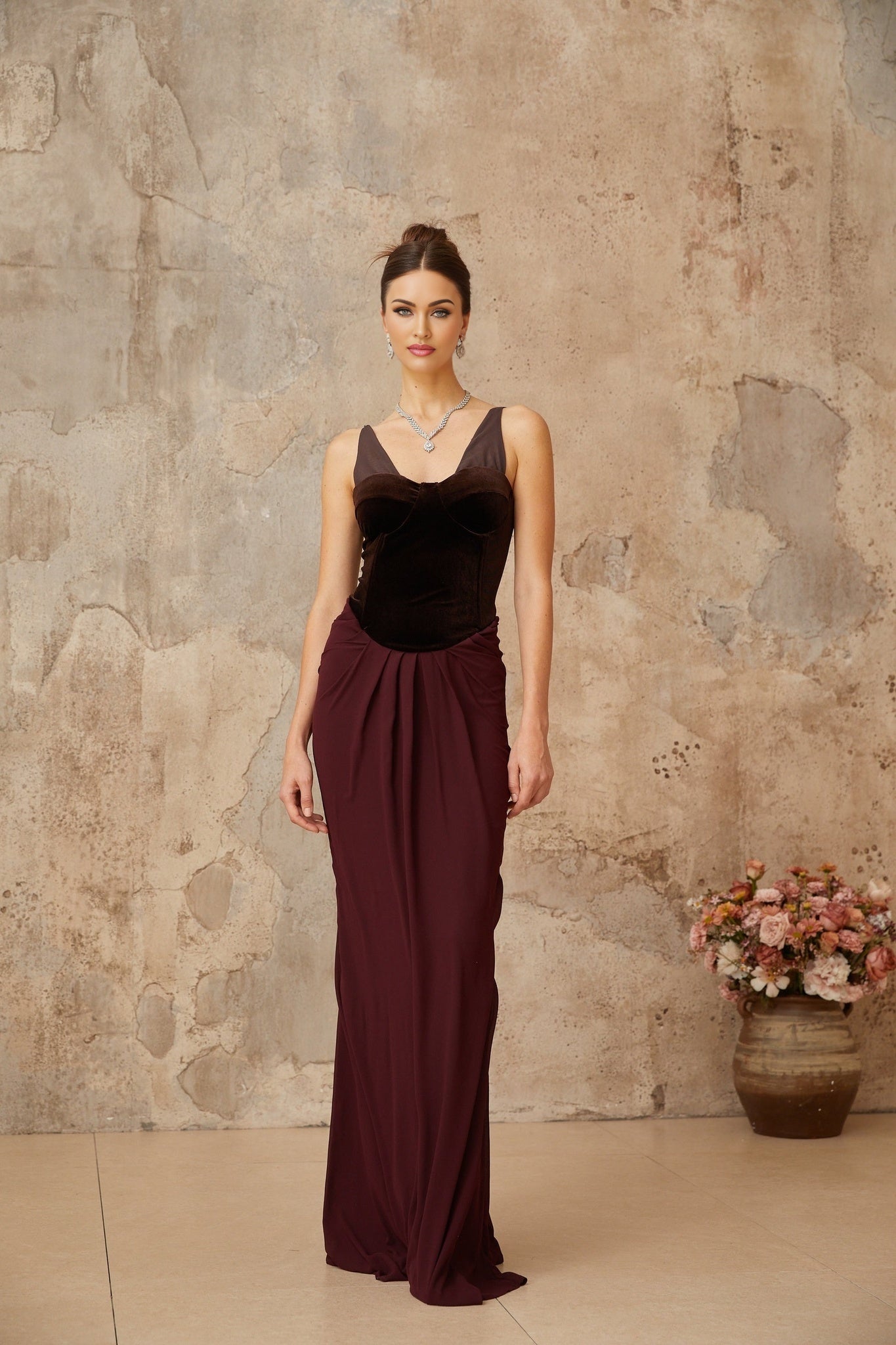 A long burgundy maxi dress with velvet panels and shirred detailing featuring a flowing silhouette and rich deep red color