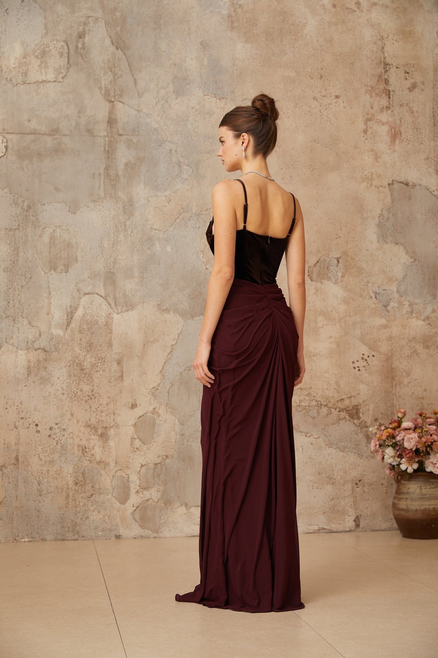A long burgundy maxi dress with velvet panels and shirred detailing throughout the body