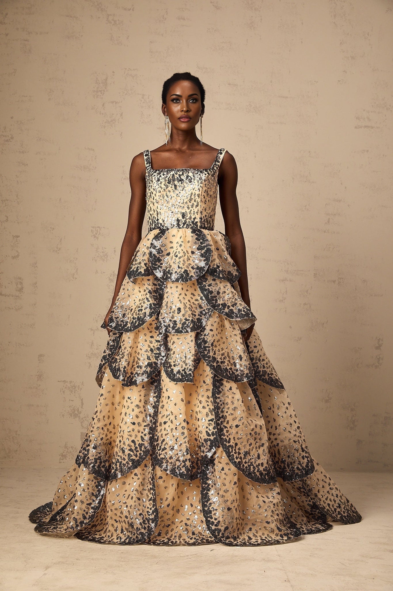 A long elegant maxi dress with tiered layers featuring shimmering sequin details and a delicate petal design throughout
