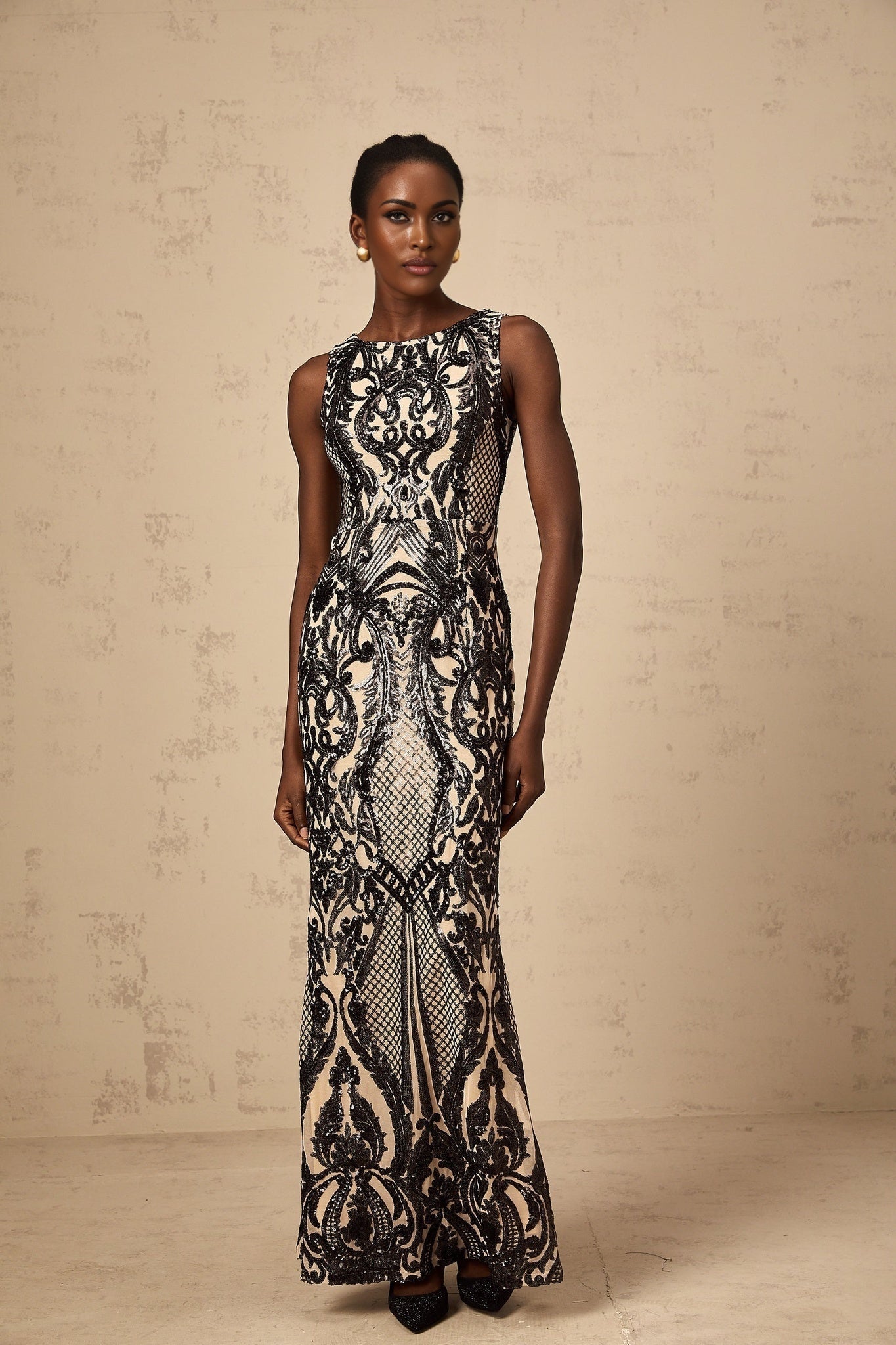 A long flowing maxi dress with sheer mesh fabric adorned with sparkling sequins creating an elegant and glamorous look