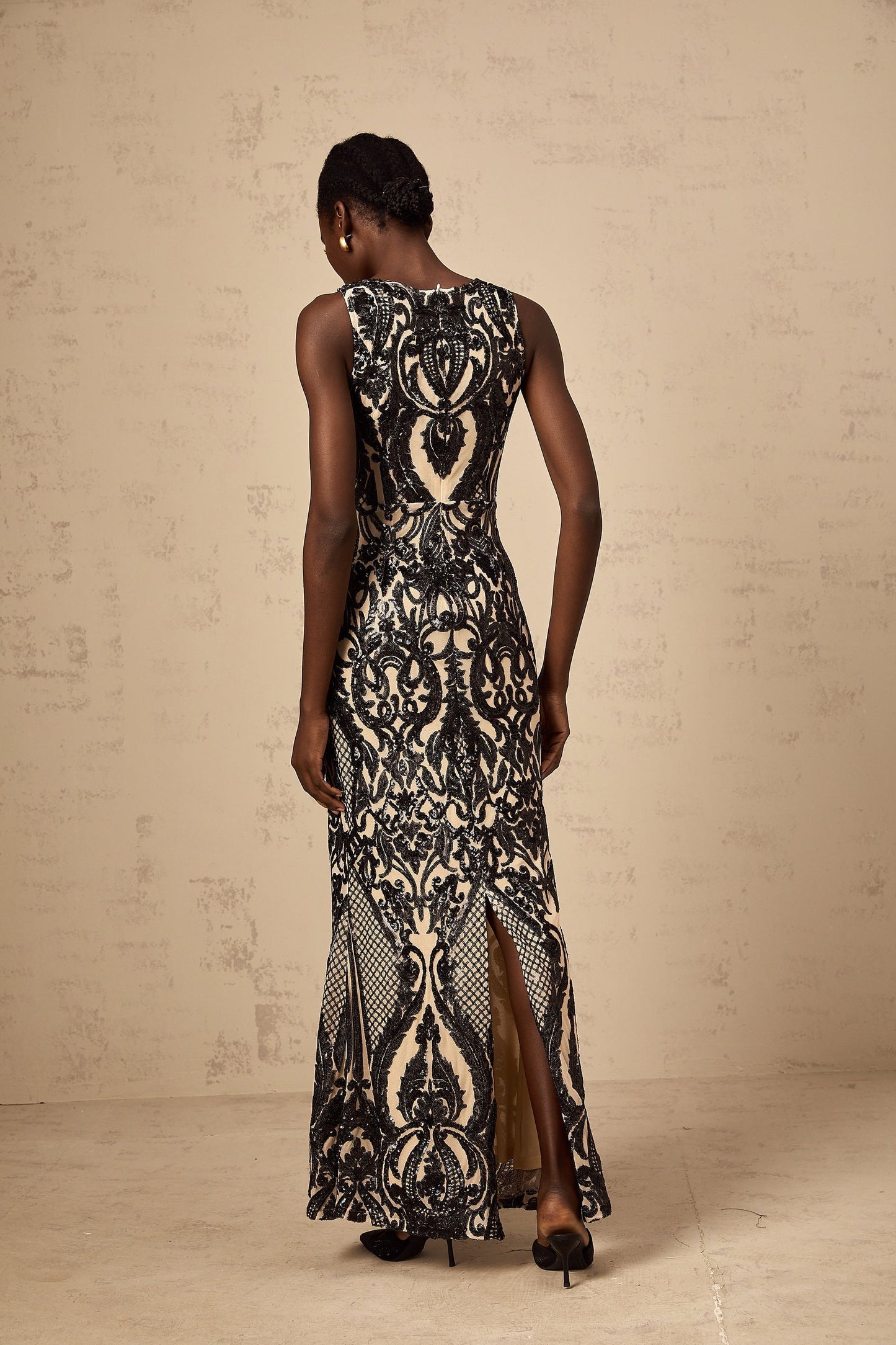 A long flowing maxi dress with sheer mesh fabric adorned with sparkly sequins creating an elegant and glamorous look