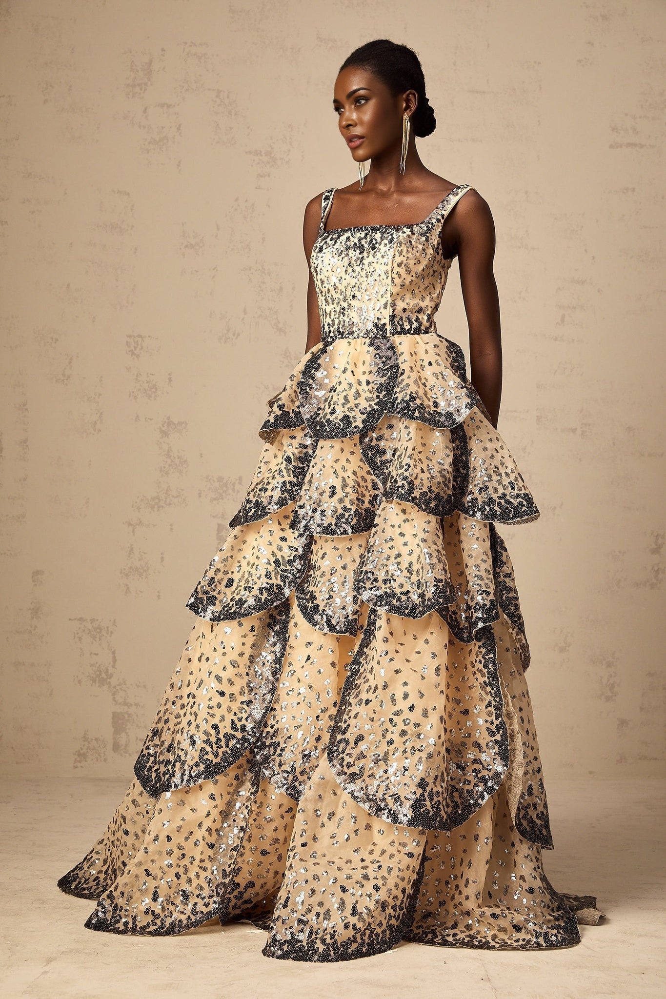 A long flowing maxi dress with tiered layers featuring shimmering sequin embellishments in a petal design