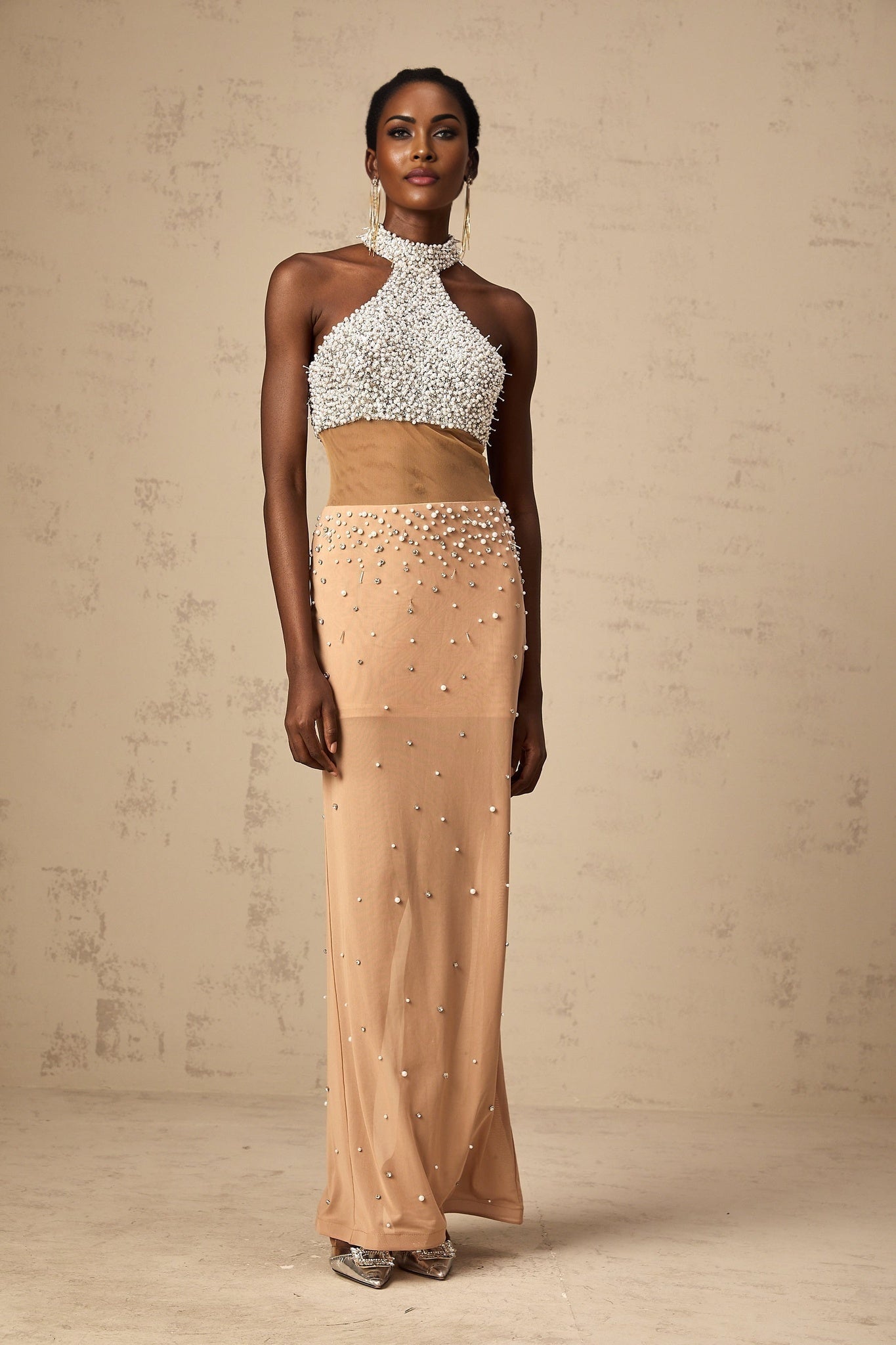 A long flowing white semi sheer maxi dress adorned with small faux pearl embellishments throughout