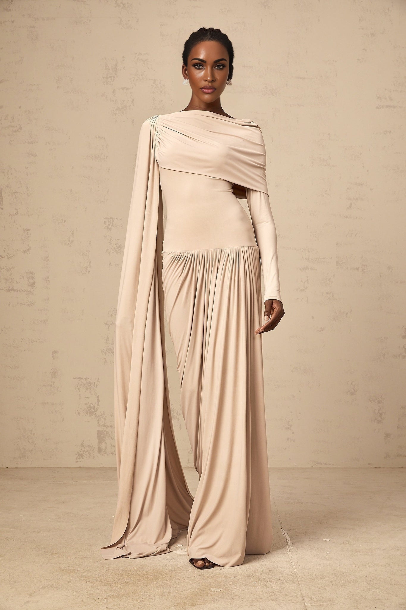 A long flowy maxi dress in neutral tones featuring a unique ribbon design and draped silhouette
