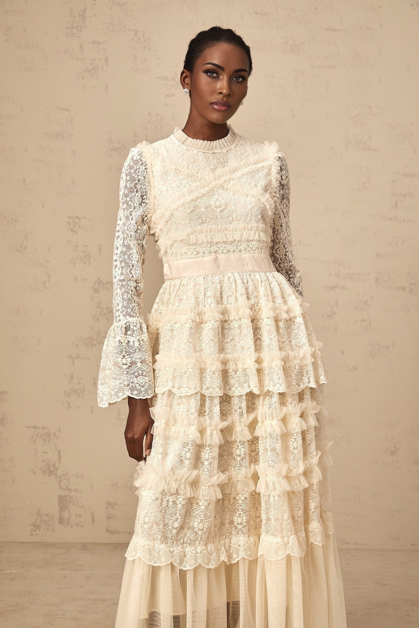 A long flowy maxi dress in neutral tones featuring lace panels and ruffled tulle details