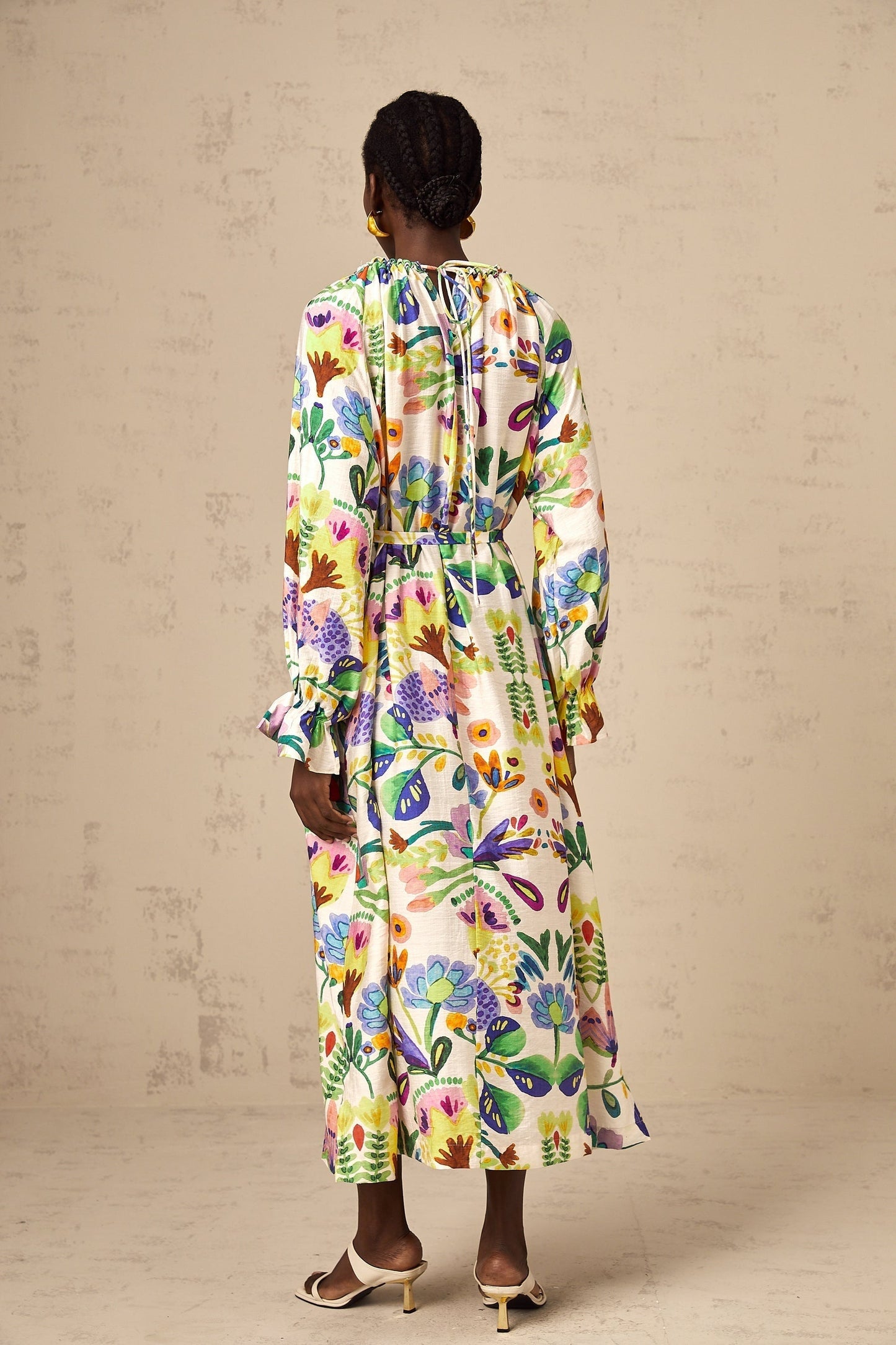 A long flowy midi dress with a colorful paisley print pattern on white poplin fabric featuring a feminine silhouette and lightweight airy design