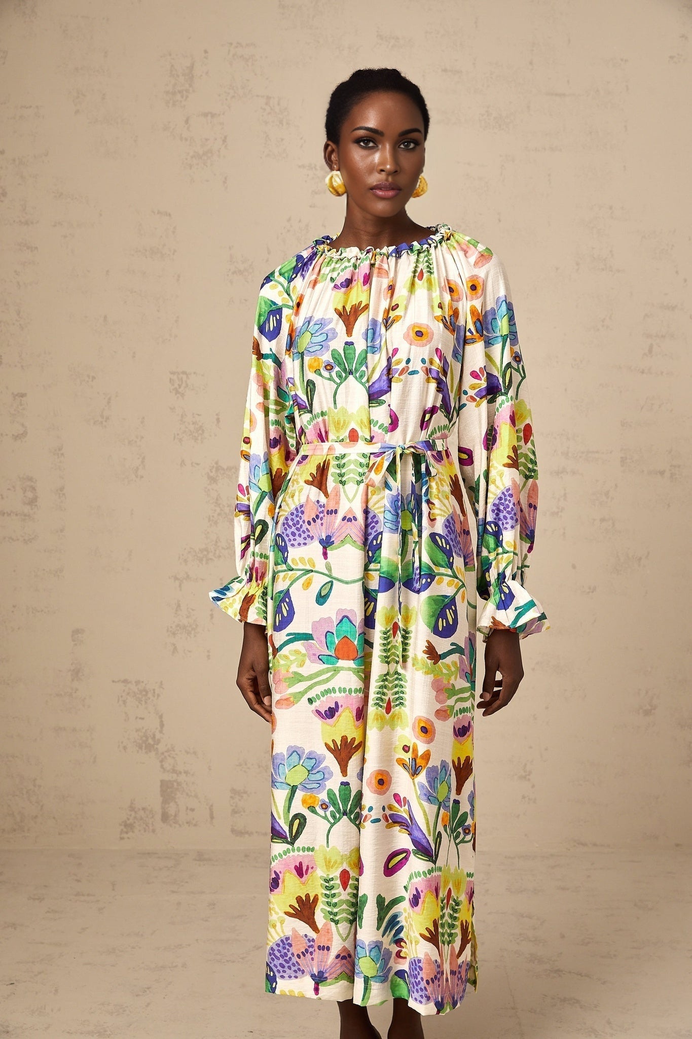A long flowy midi dress with a colorful paisley print pattern on white poplin fabric featuring a fitted waist and loose skirt