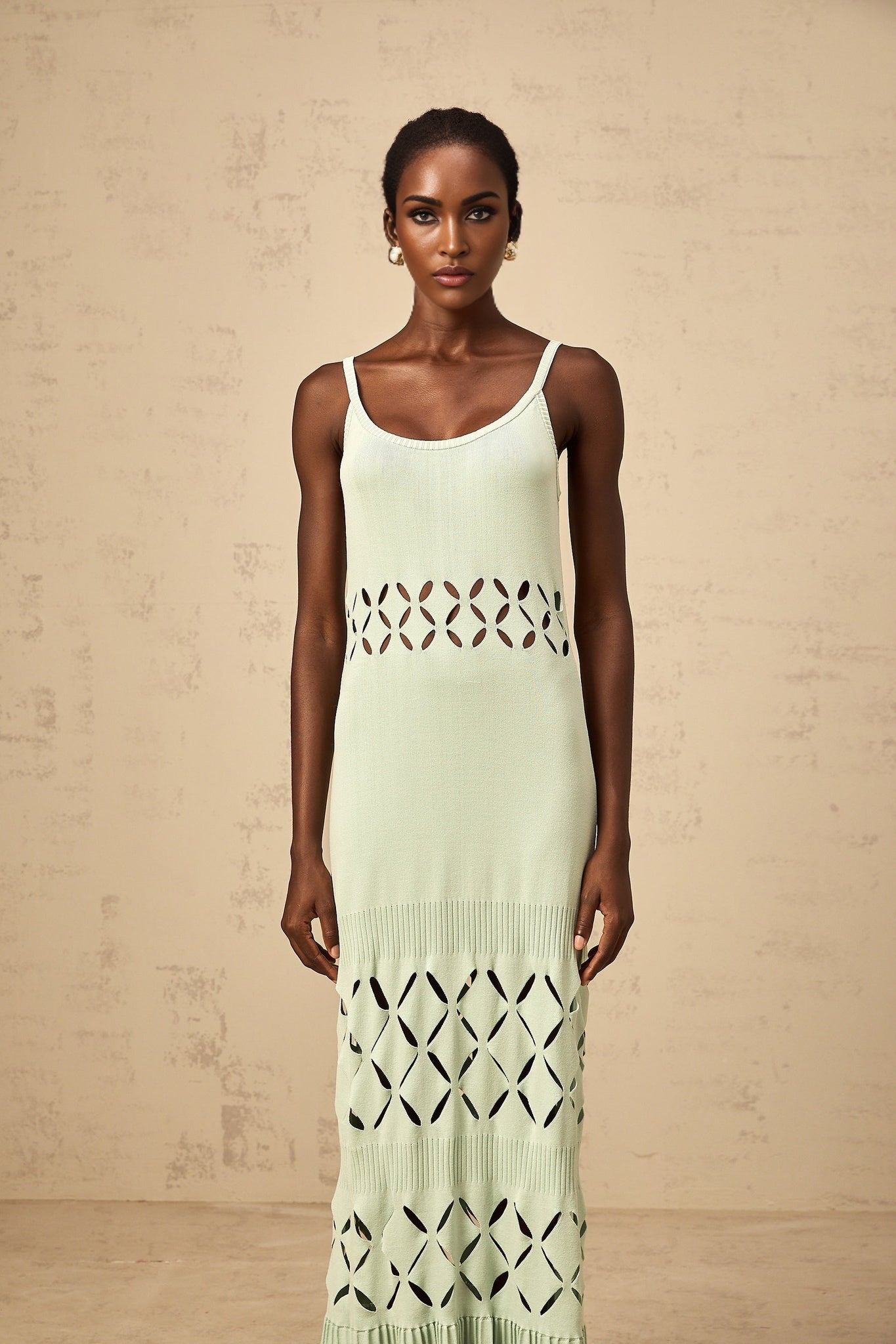 A long green knitted maxi dress with cutout details featuring a flowy silhouette and intricate knit pattern