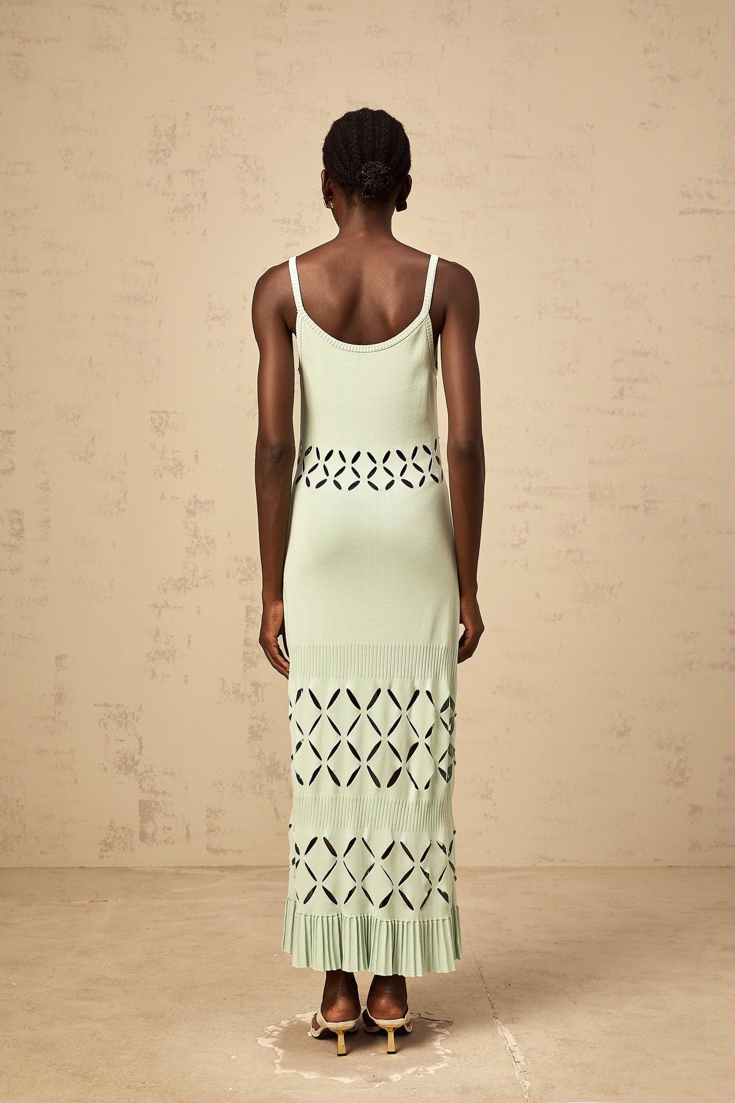 A long green knitted maxi dress with cutout details featuring a formfitting silhouette and a floorlength skirt