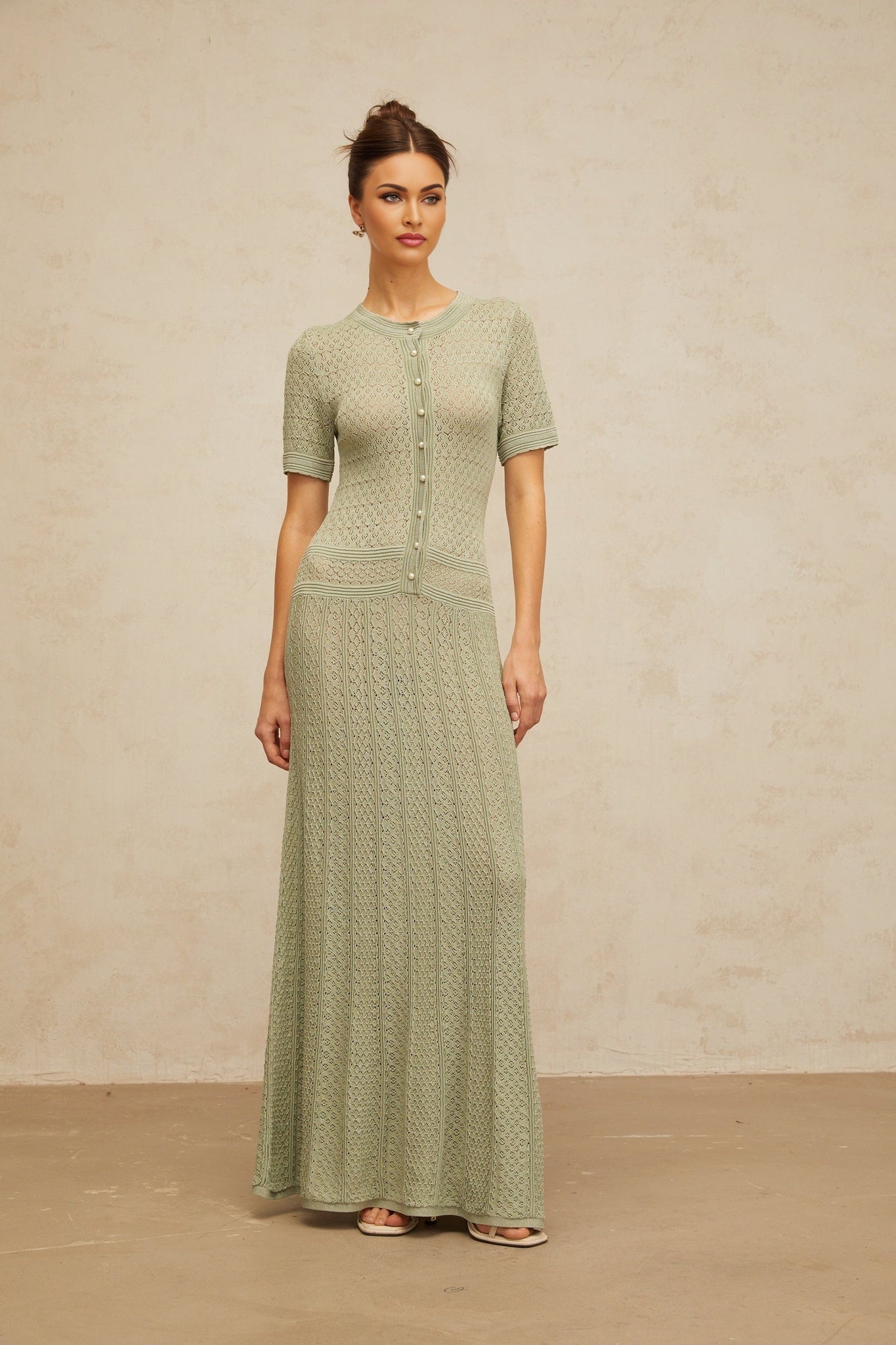 A long green maxi dress with shirred detailing and crochet knit fabric styled on a model