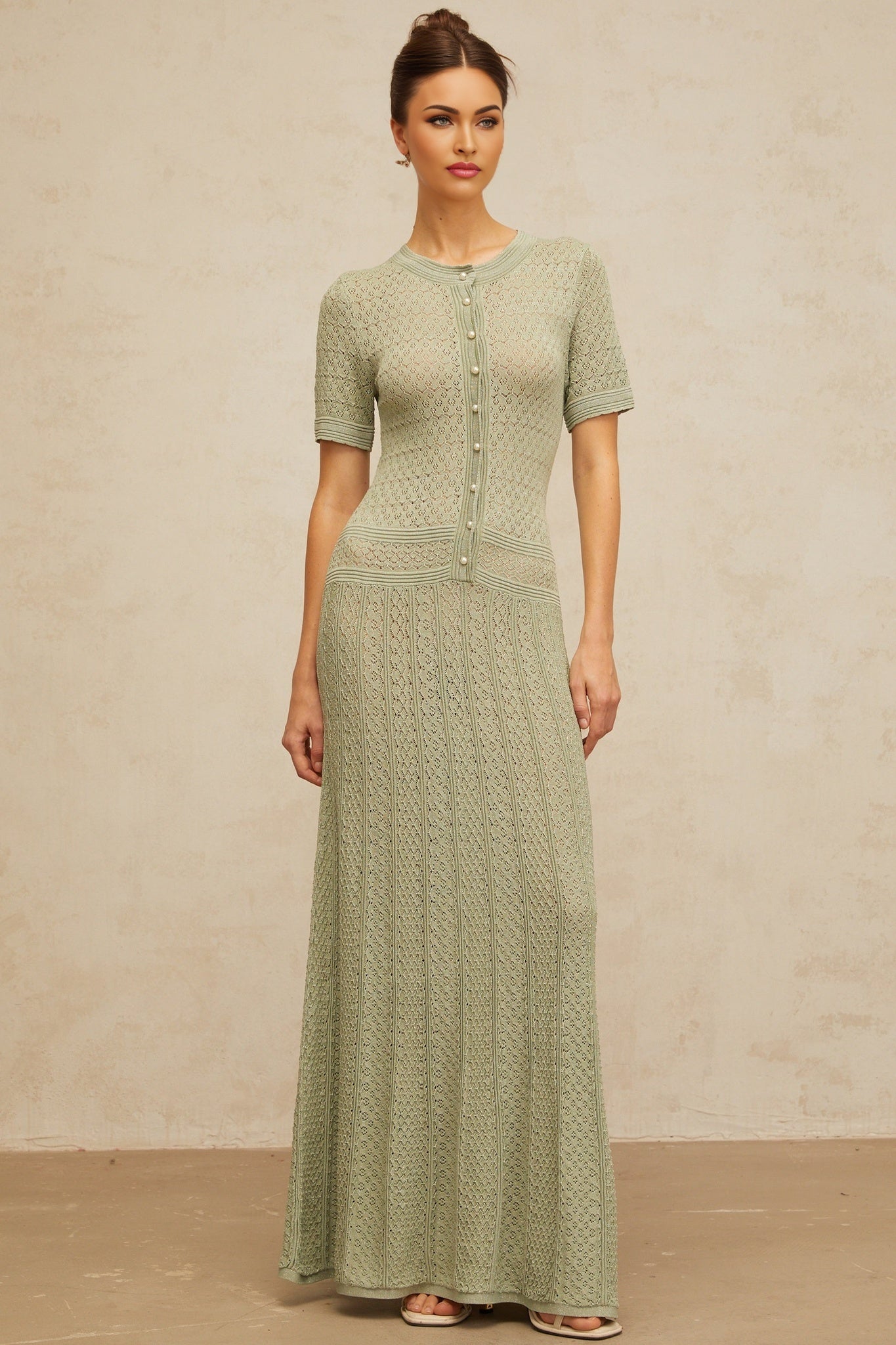 A long green maxi dress with shirred detailing and crochet knit texture featuring a fitted bodice and flowing skirt