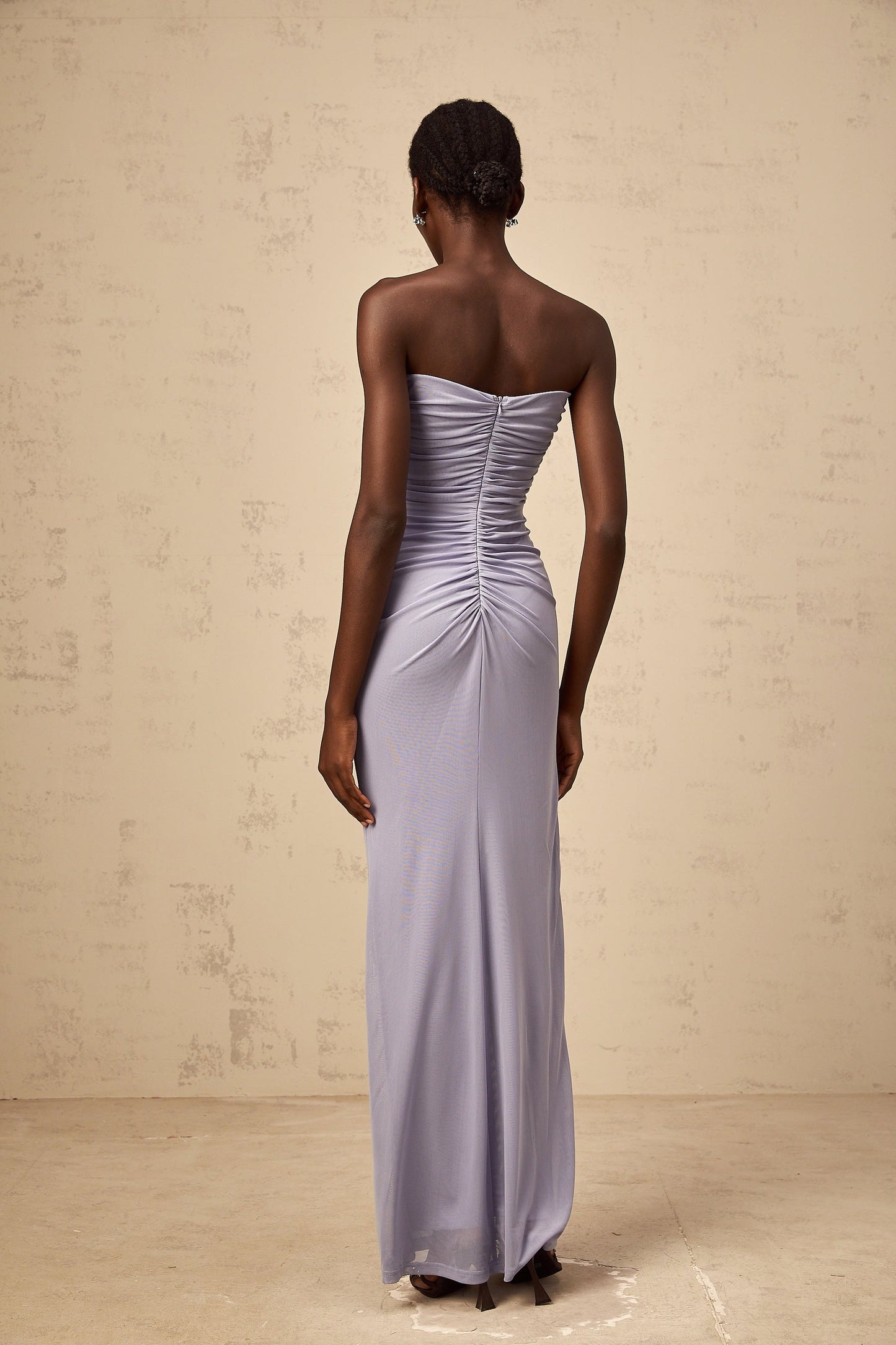 A long lavender maxi dress with a corsetstyle bodice featuring ruched 3D petal details and a flowing skirt