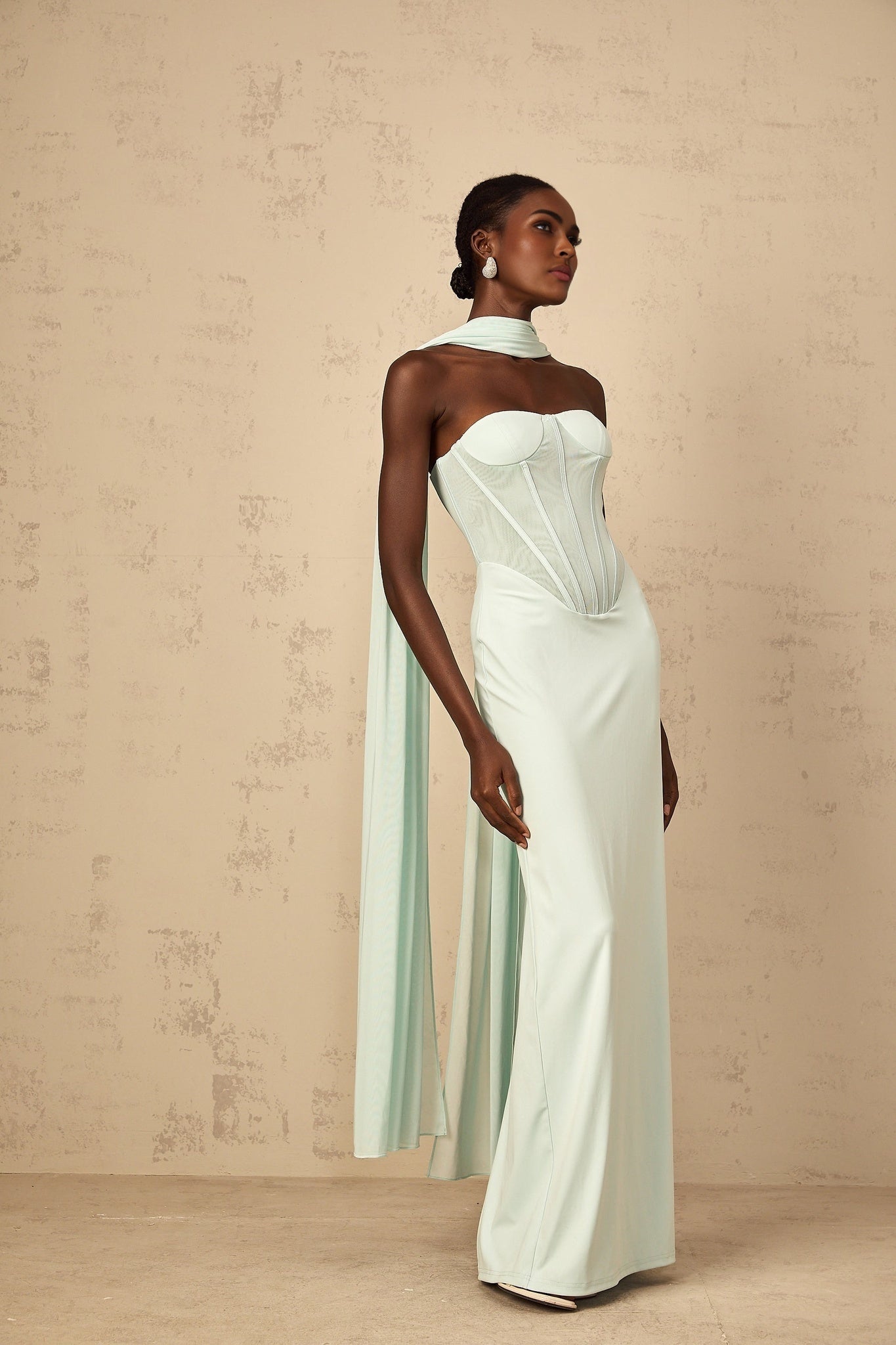 A long mint green dress with a tulle skirt and corset bodice featuring sheer panels