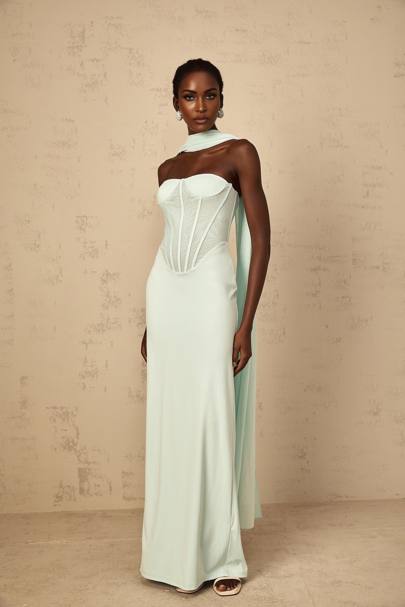 A long mint green maxi dress with a corset bodice and tulle panel details featuring a flowy skirt and delicate straps