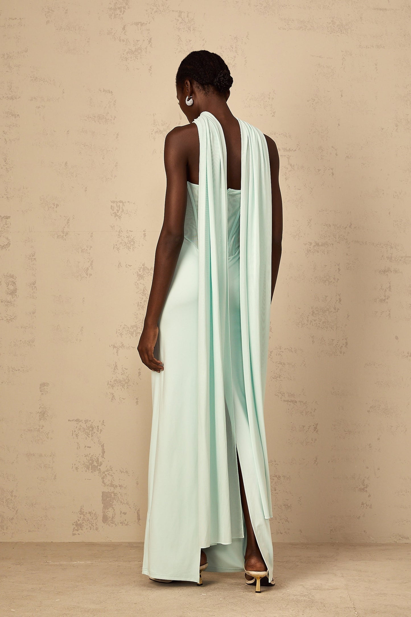 A long mint green maxi dress with a tulle panel and corset bodice featuring thin straps and a flowy skirt