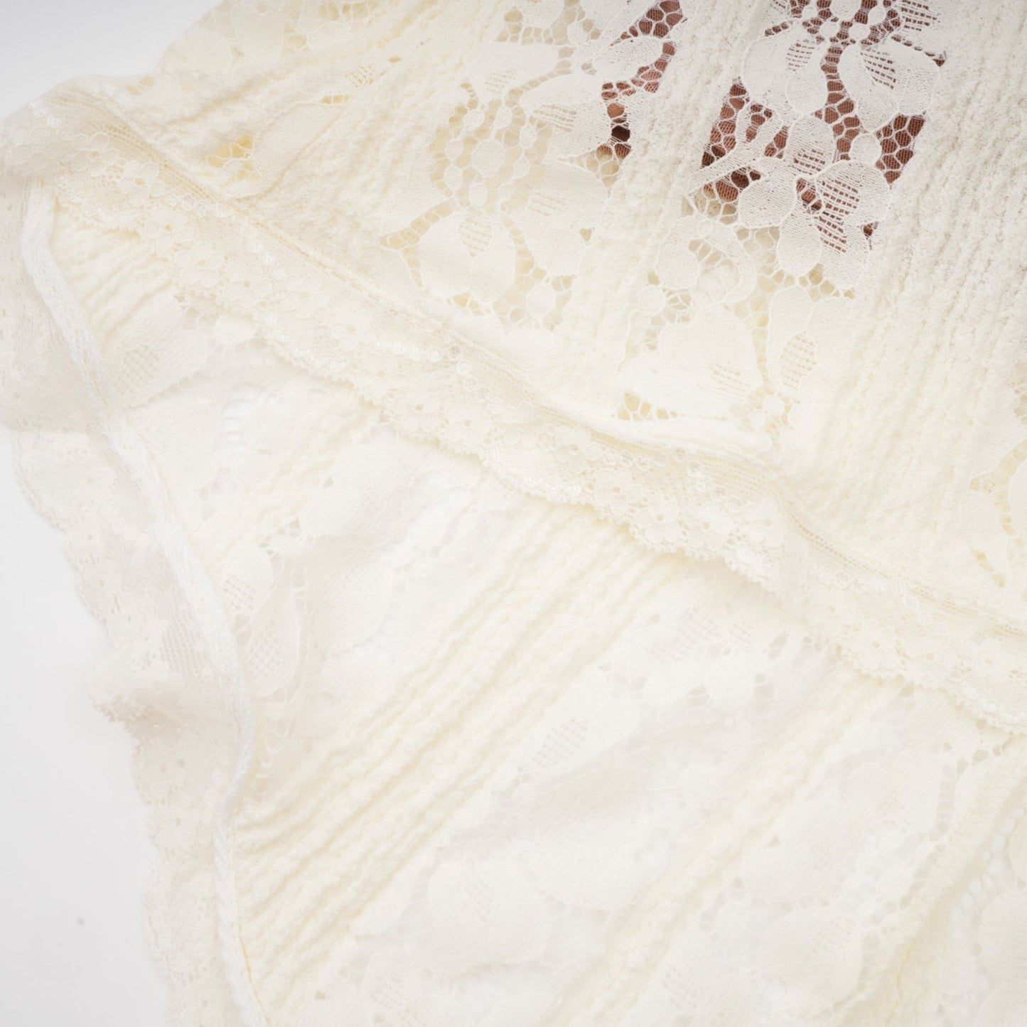 A long neutral colored maxi dress with floral lace detailing and a train design featuring a fitted bodice and flowing skirt