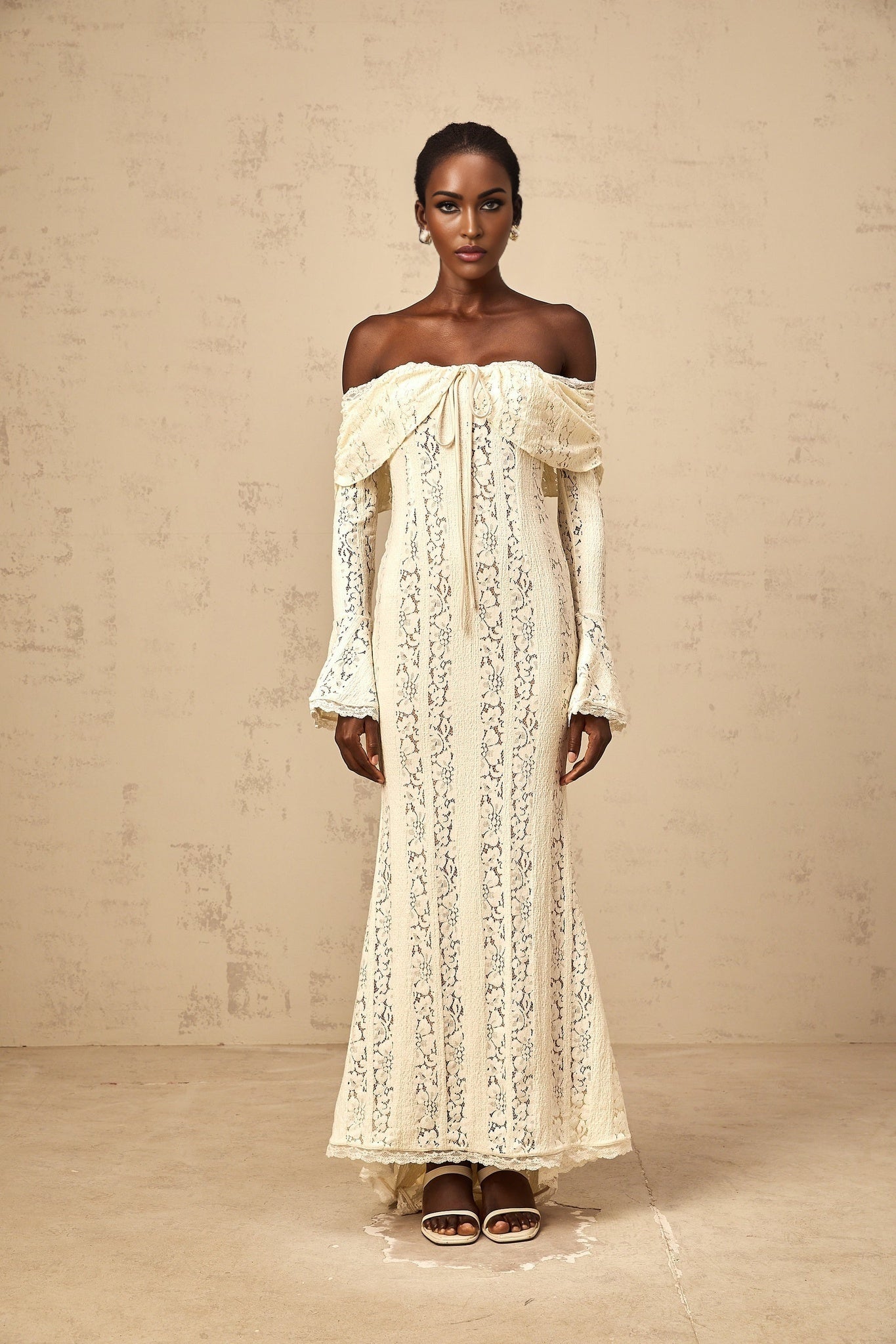 A long neutral colored maxi dress with floral lace detailing and a train design named Emeline