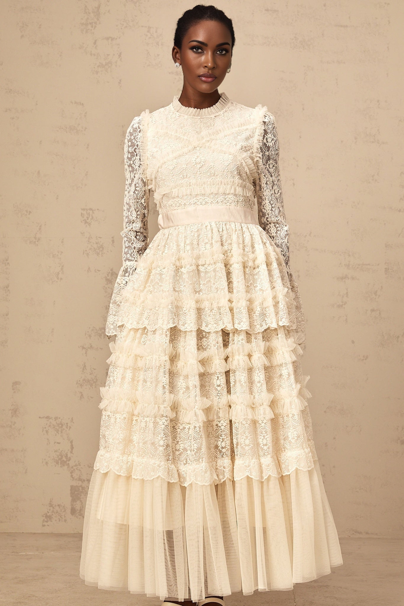A long neutral colored maxi dress with lace panels and ruffled tulle details