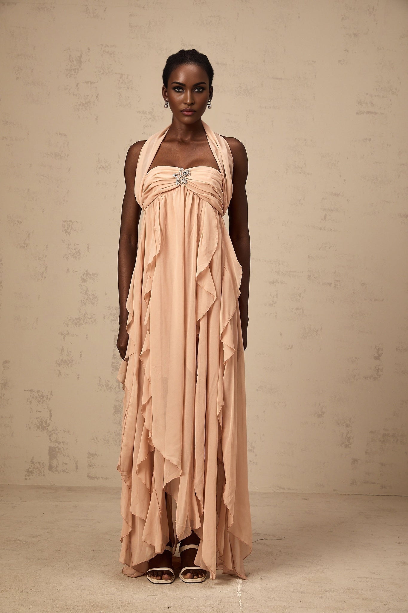 A long pink chiffon maxi dress with a halter neck and ruffle details