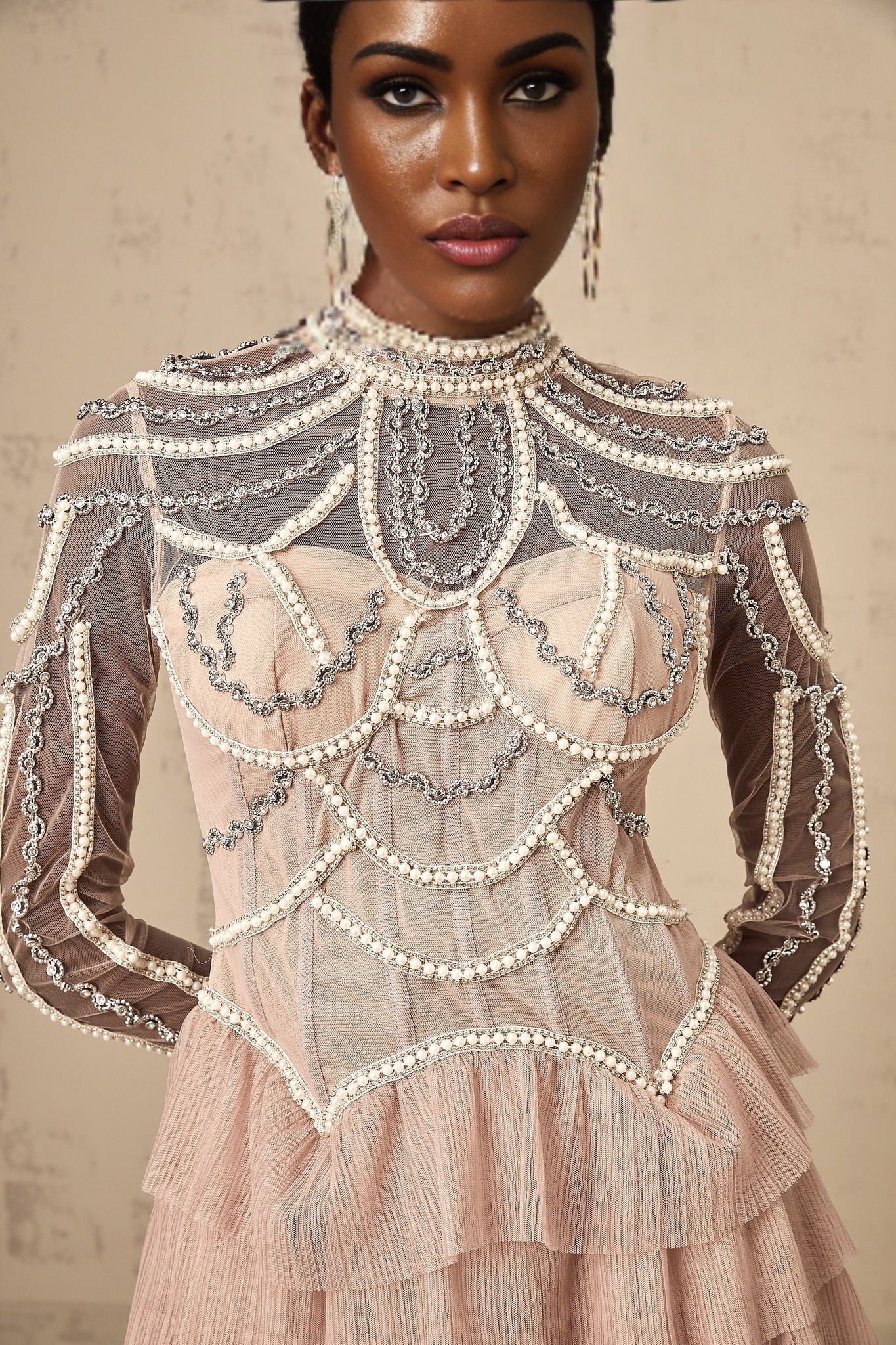 A long pink gown with tiered layers of semisheer fabric and delicate beaded embellishments