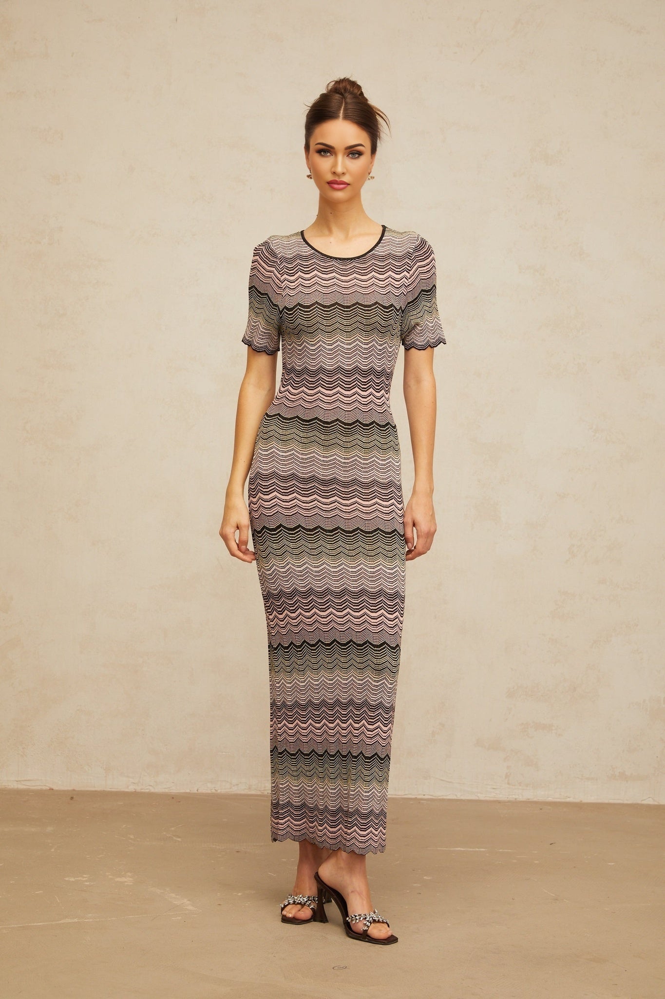 A long pink maxi dress with a wavy crochet knit pattern and a flowing silhouette