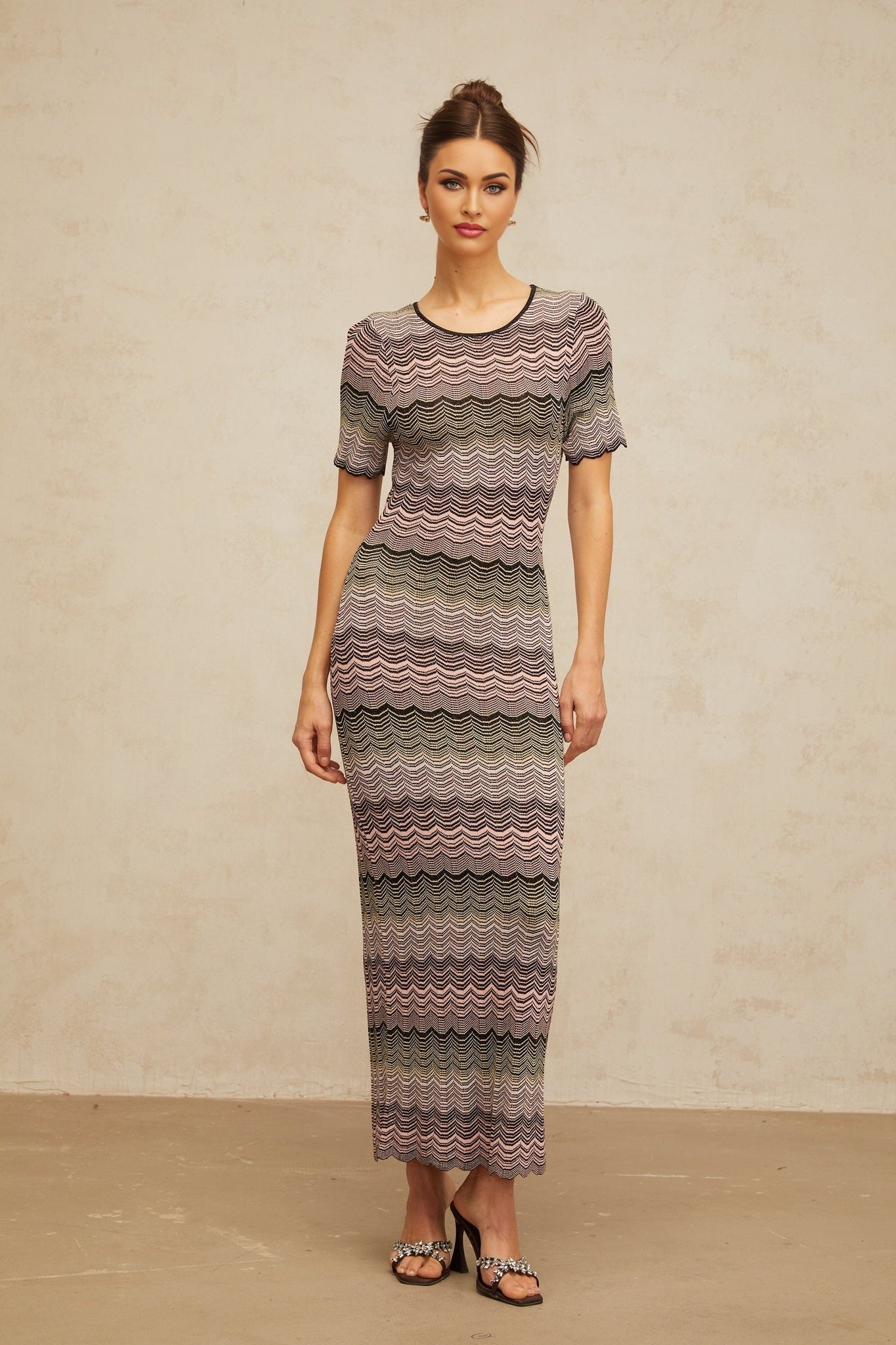 A long pink maxi dress with a wavy crochet knit pattern featuring a flowing silhouette and intricate texture throughout