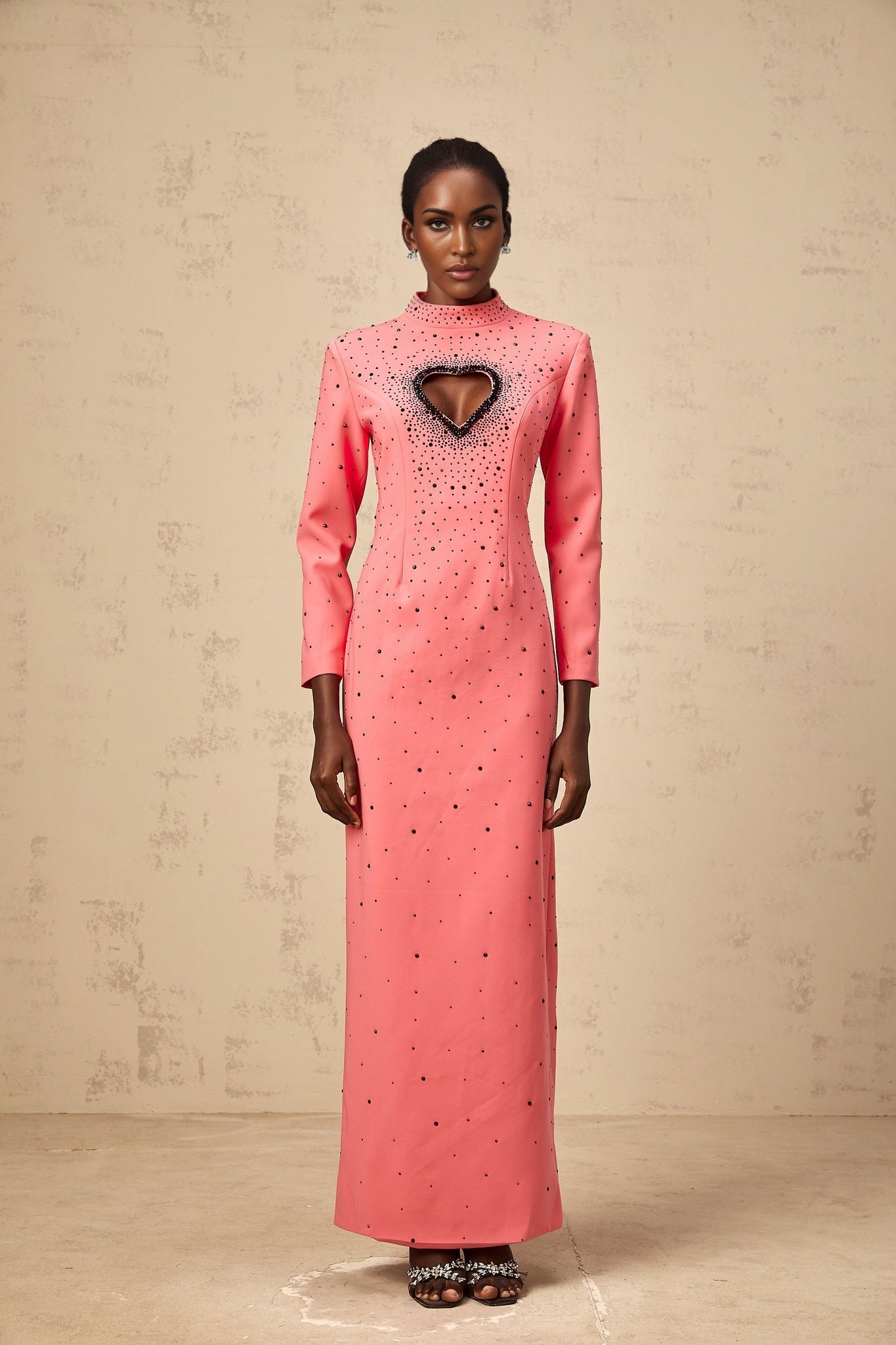 A long pink maxi dress with heart shaped cutouts and embellishments