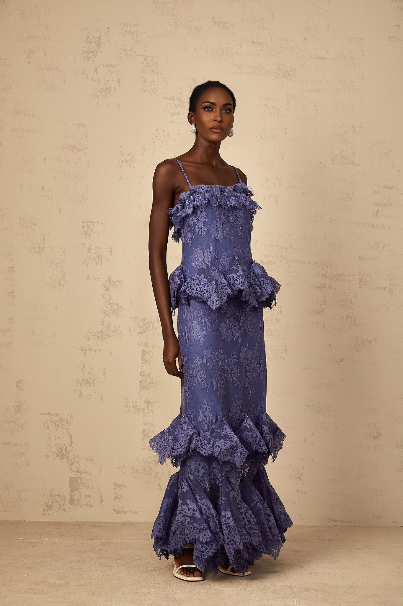 A long purple maxi dress with floral lace pattern and ruffled details featuring a feminine silhouette