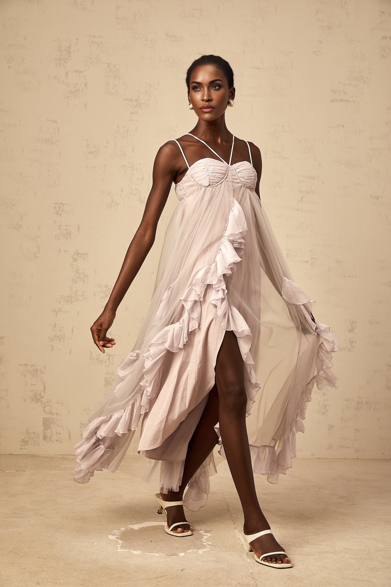 A long purple maxi dress with multiple layers of ruffled tulle fabric creating a voluminous and ethereal silhouette