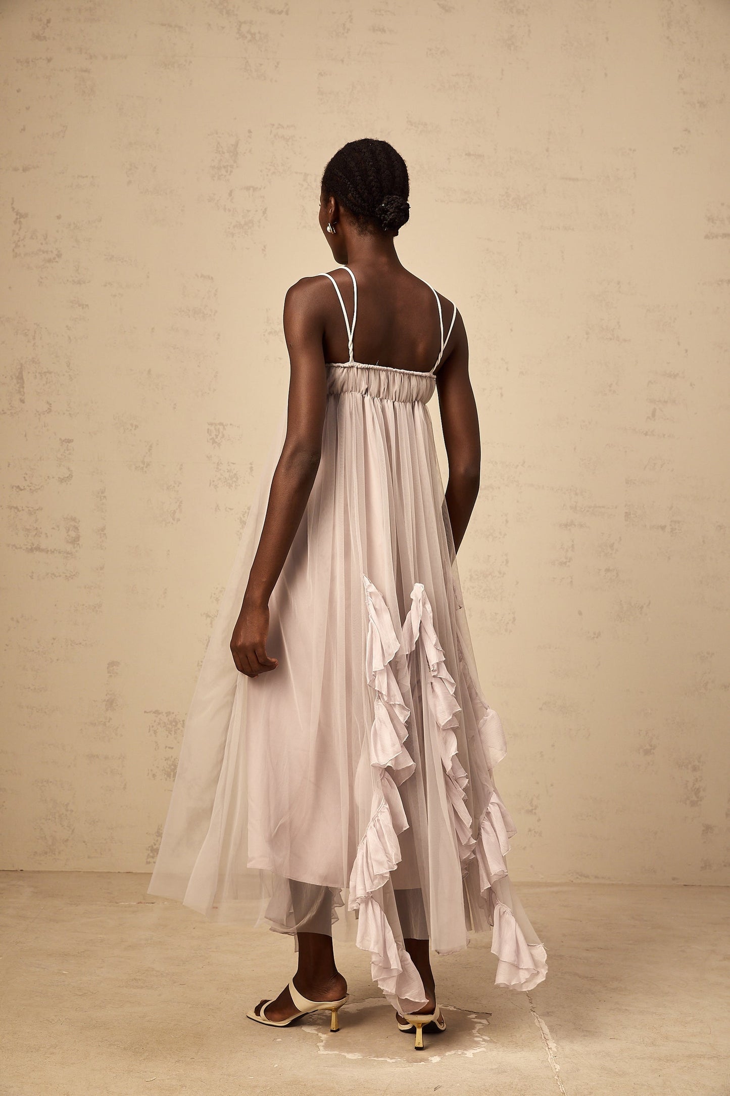 A long purple maxi dress with multiple layers of ruffled tulle fabric creating a voluminous and romantic silhouette