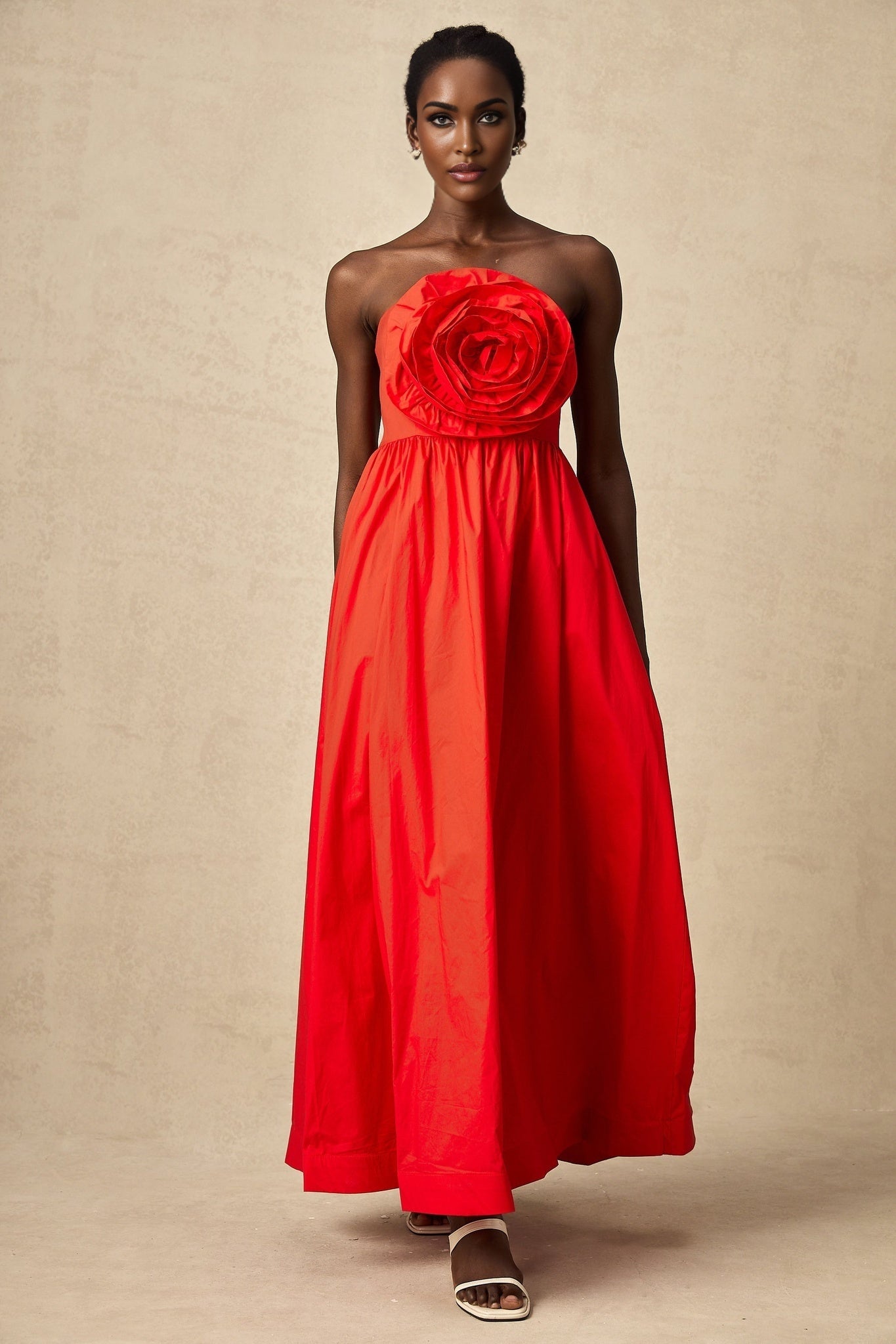 A long red maxi dress with 3d petal ruffles covering the bodice and skirt creating a textured floral effect