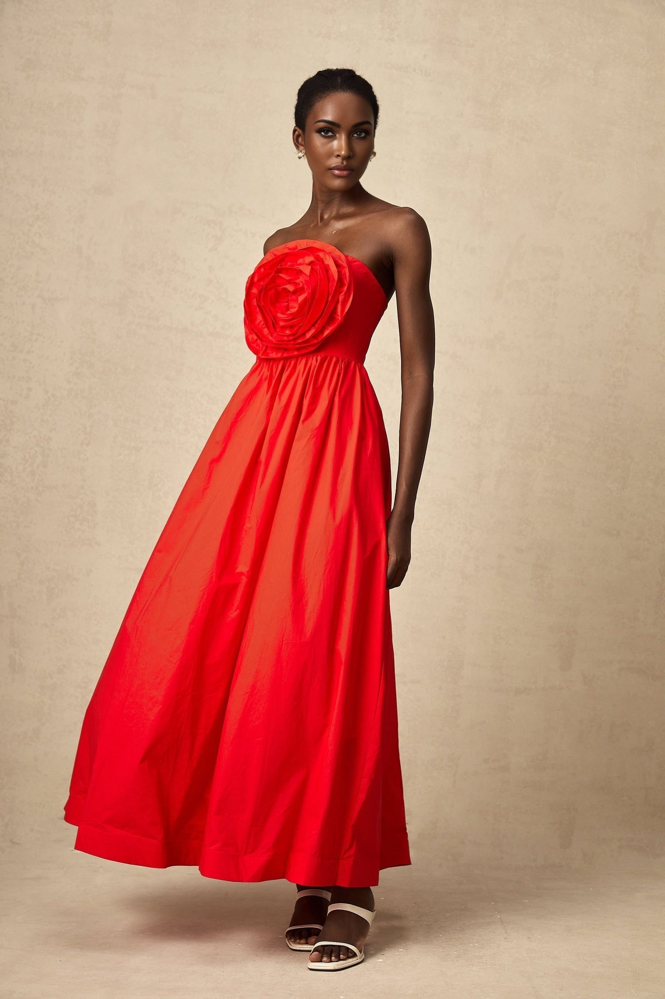 A long red maxi dress with 3d petal ruffles covering the entire garment creating a textured floral appearance
