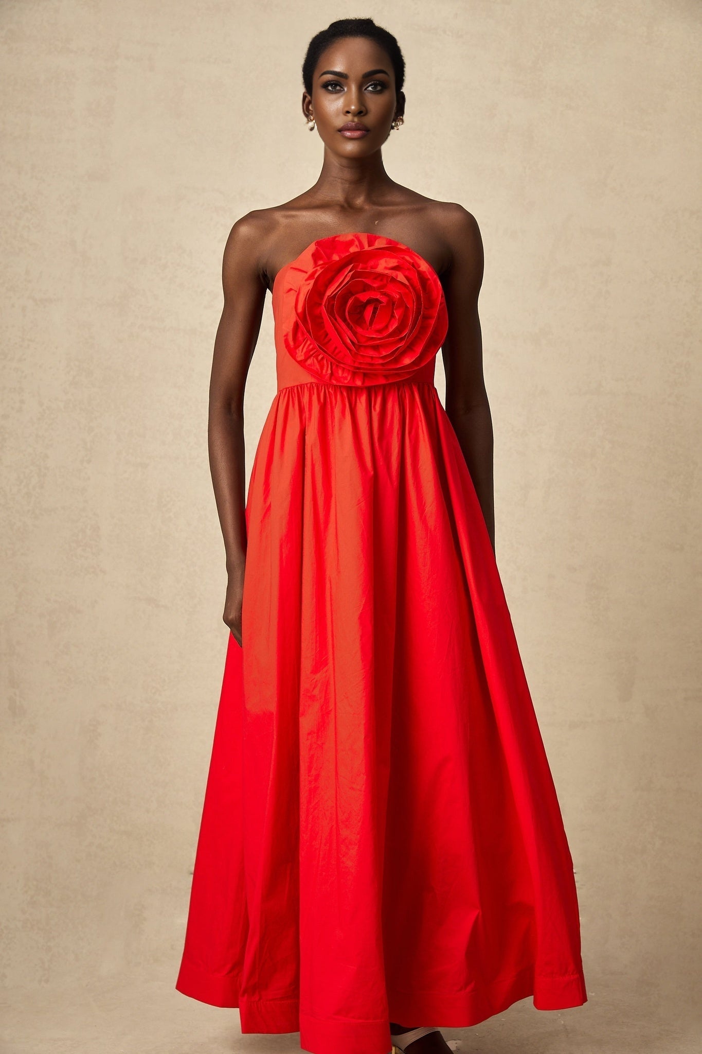 A long red maxi dress with ruffled 3d petal details covering the bodice and skirt creating a textured floral effect