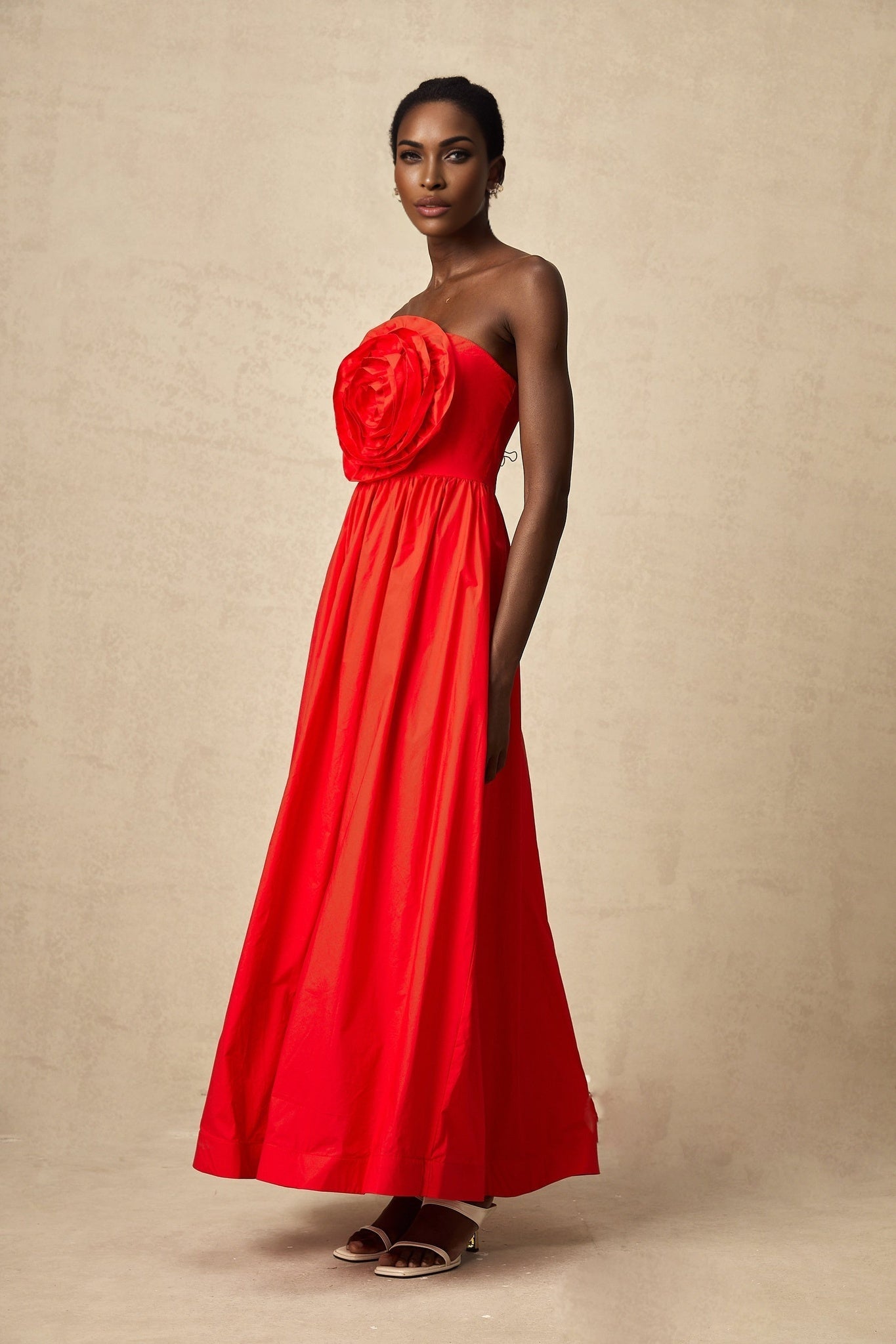 A long red maxi dress with ruffled 3d petal details covering the entire garment creating a textured floral effect