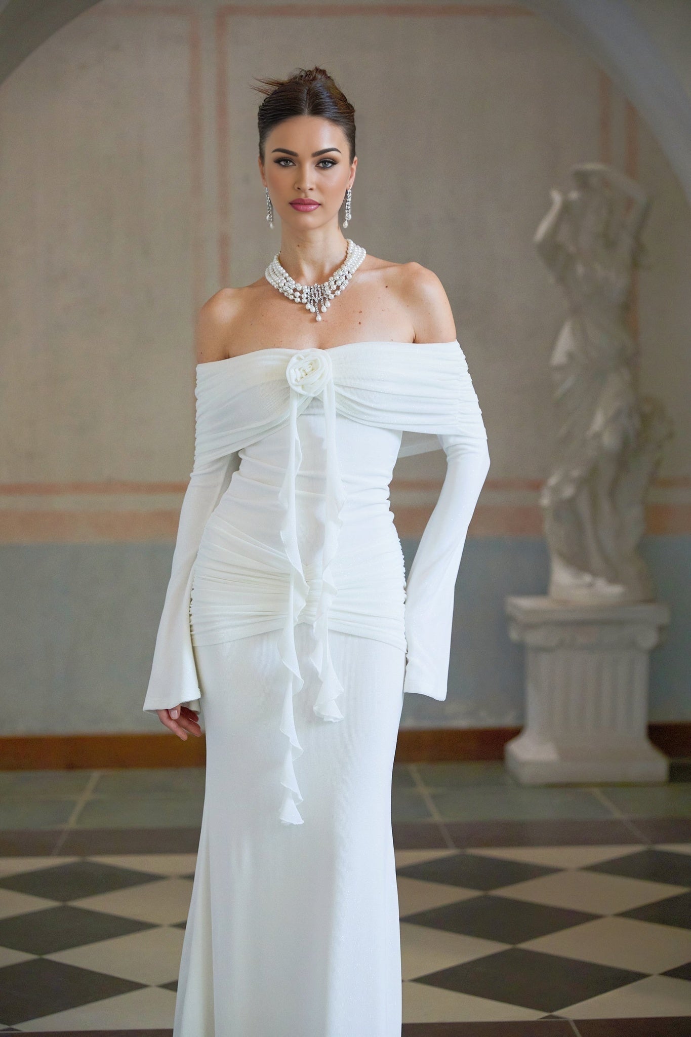 A long white knit maxi dress with glittery floral appliques decorating the fabric