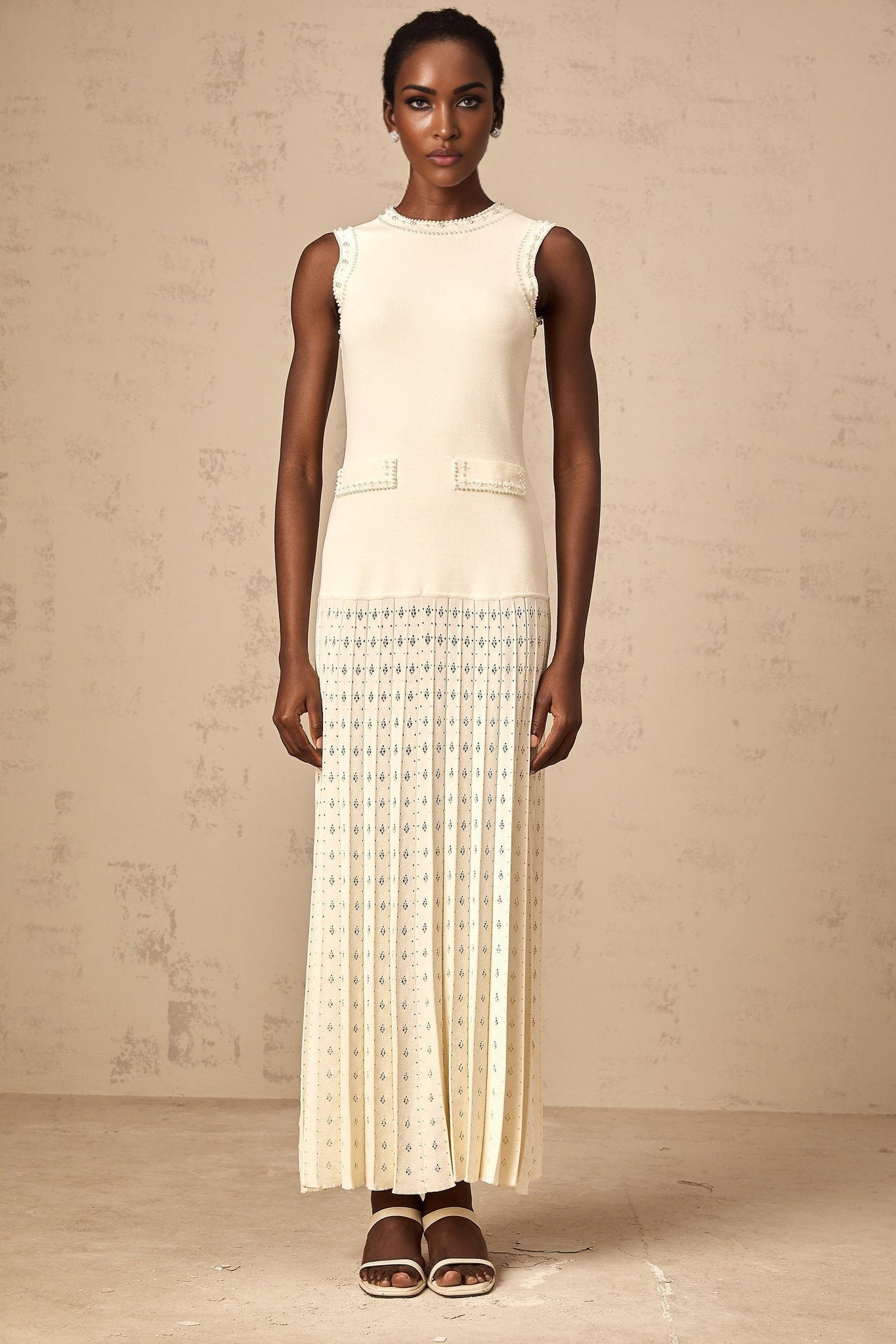 A long white knitted maxi dress adorned with faux pearl embellishments