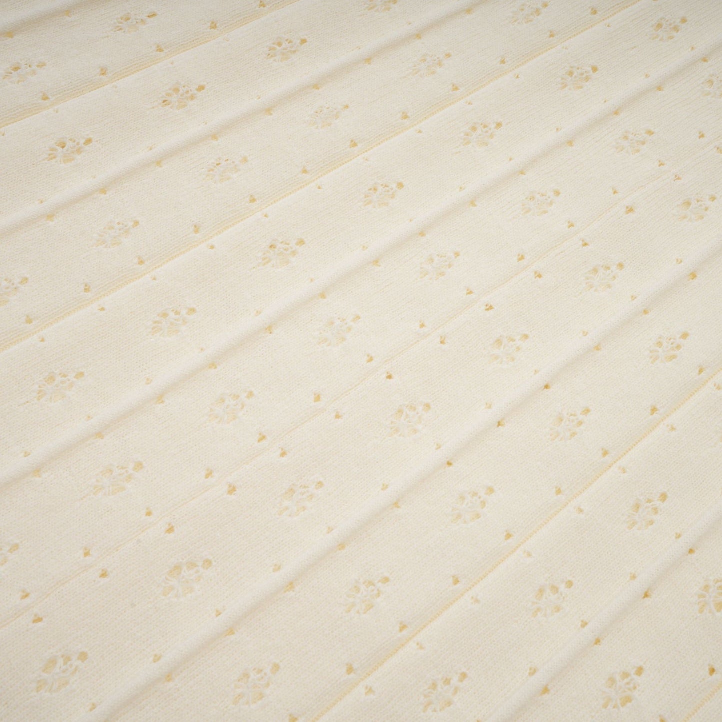A long white knitted maxi dress with faux pearl embellishments throughout the fabric