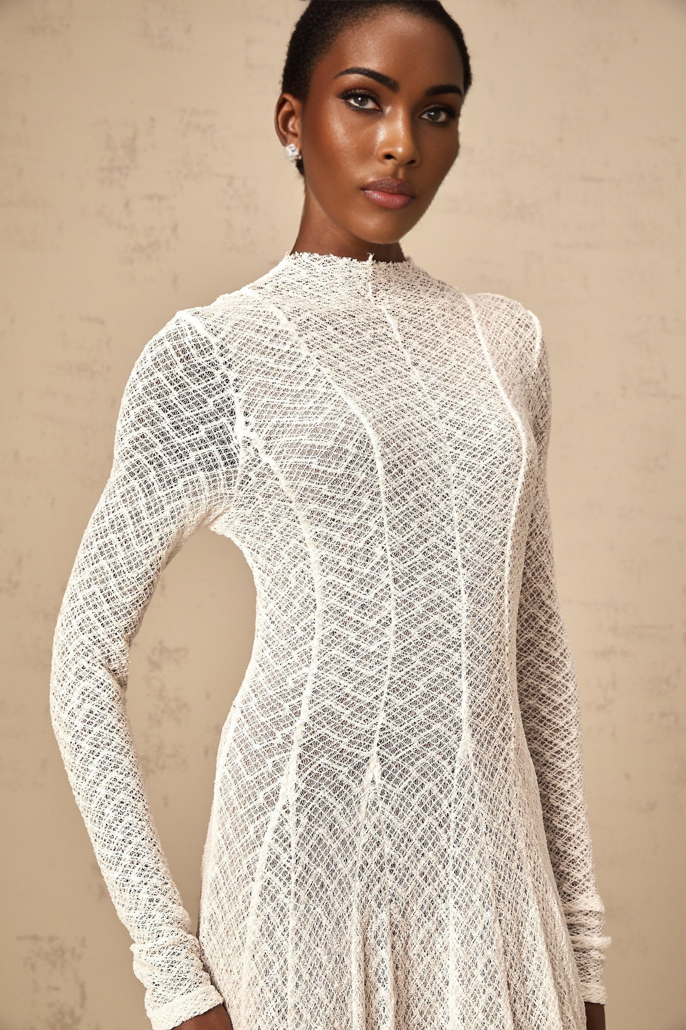 A long white lace maxi dress with a wavy pattern design and feminine silhouette