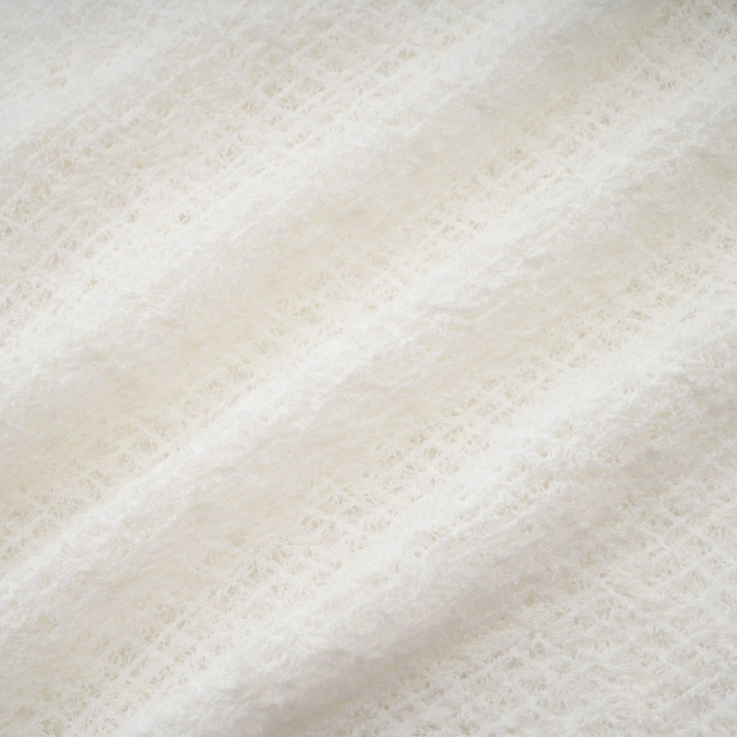 A long white lace maxi dress with a wavy pattern throughout featuring a fitted bodice and flowing skirt