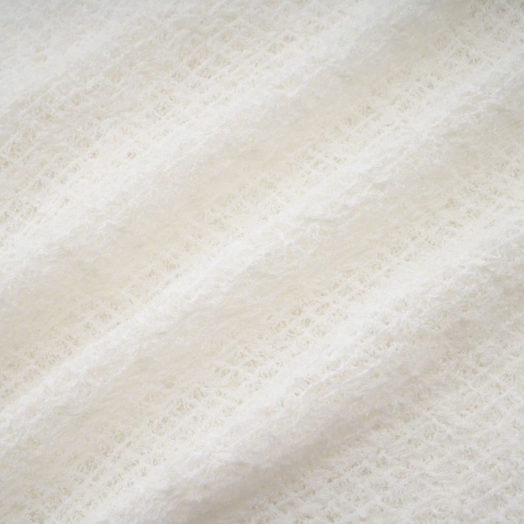 A long white lace maxi dress with a wavy pattern throughout featuring a fitted bodice and flowing skirt