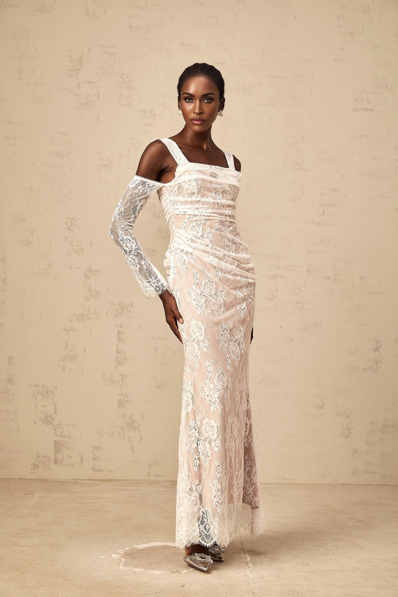 A long white maxi dress with a floral lace pattern featuring a corset style bodice with ruched detailing named Berenice