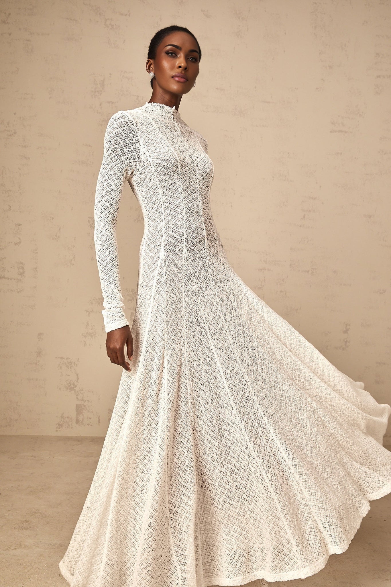 A long white maxi dress with a wavy lace pattern covering the entire garment The dress features a feminine silhouette and delicate details