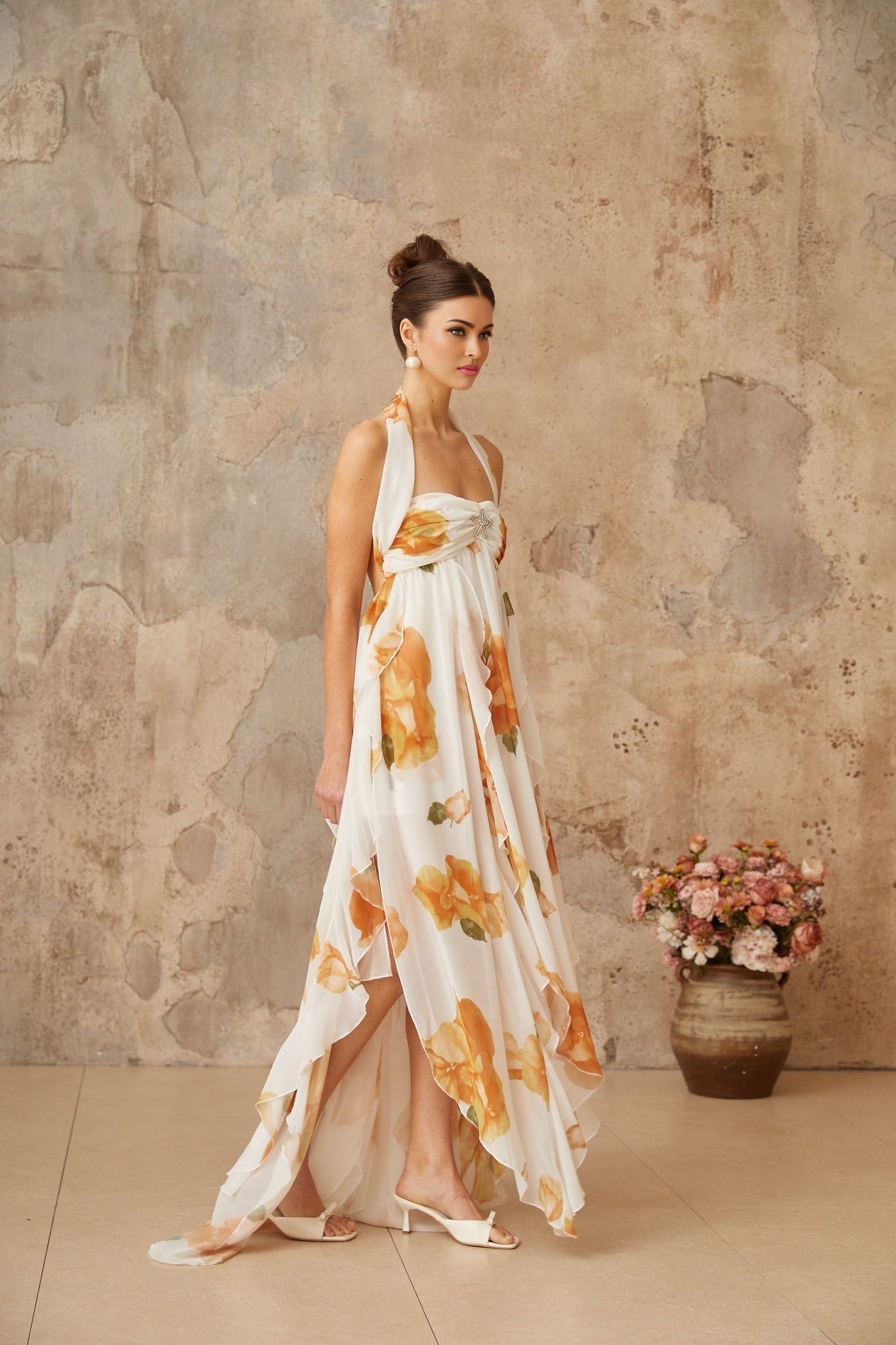 A long white maxi dress with floral print and ruffled tulle details featuring a fitted bodice and flowing skirt