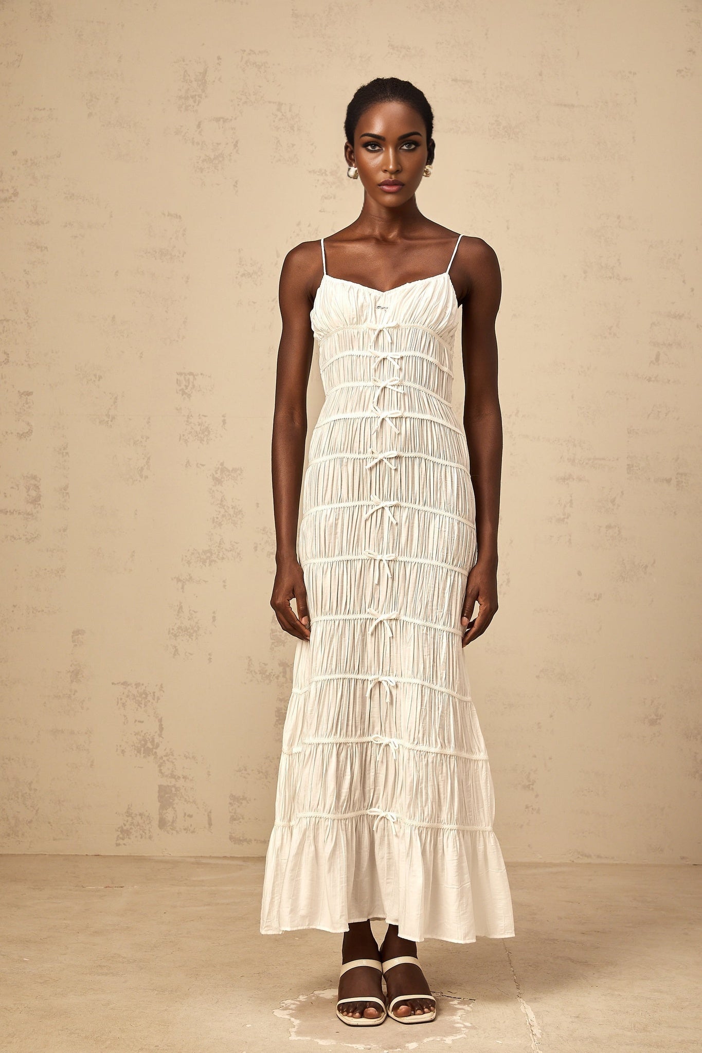 A long white maxi dress with smocked detailing and a large bowknot accent