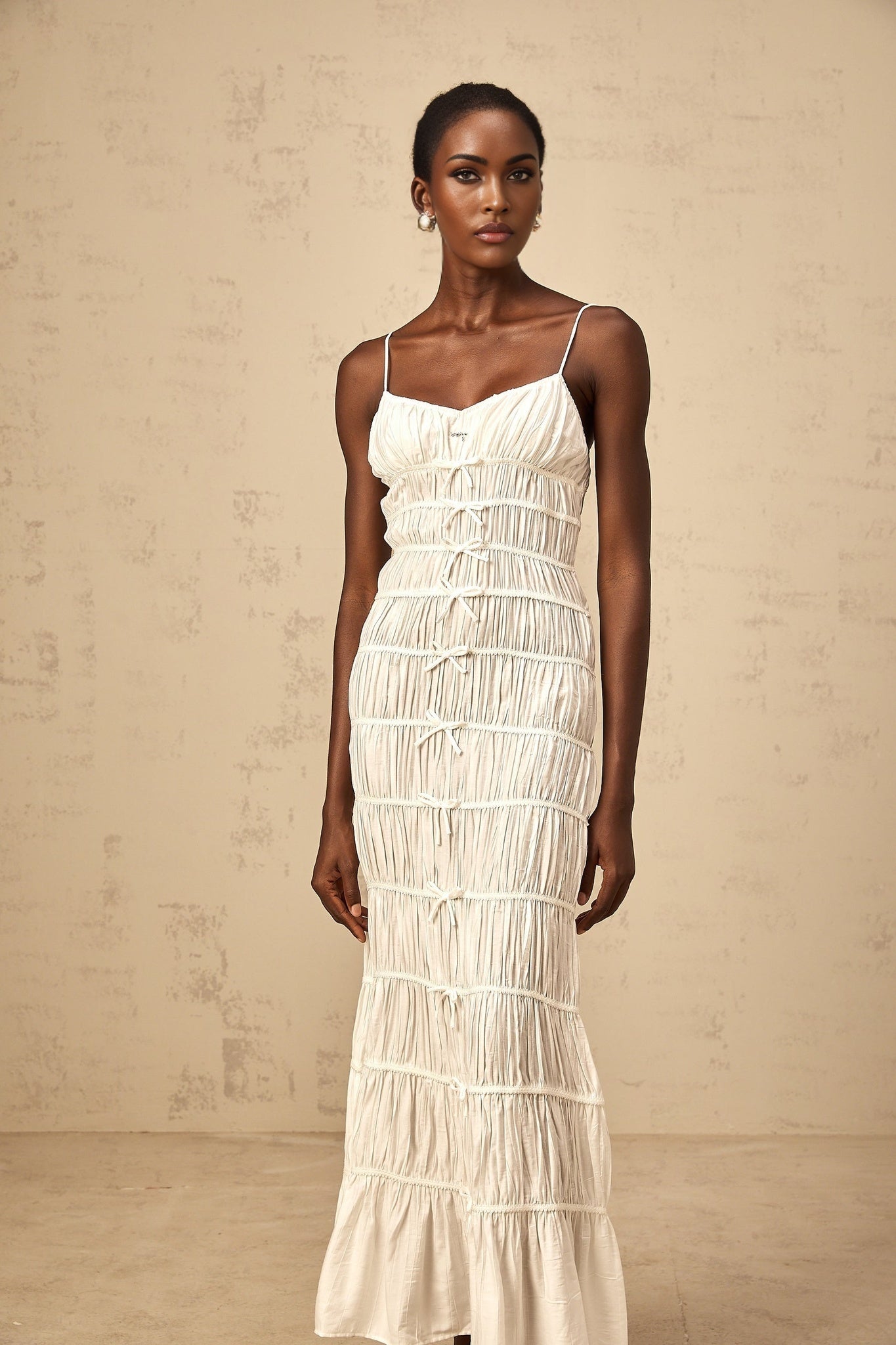 A long white maxi dress with smocking and a decorative bow knot detail