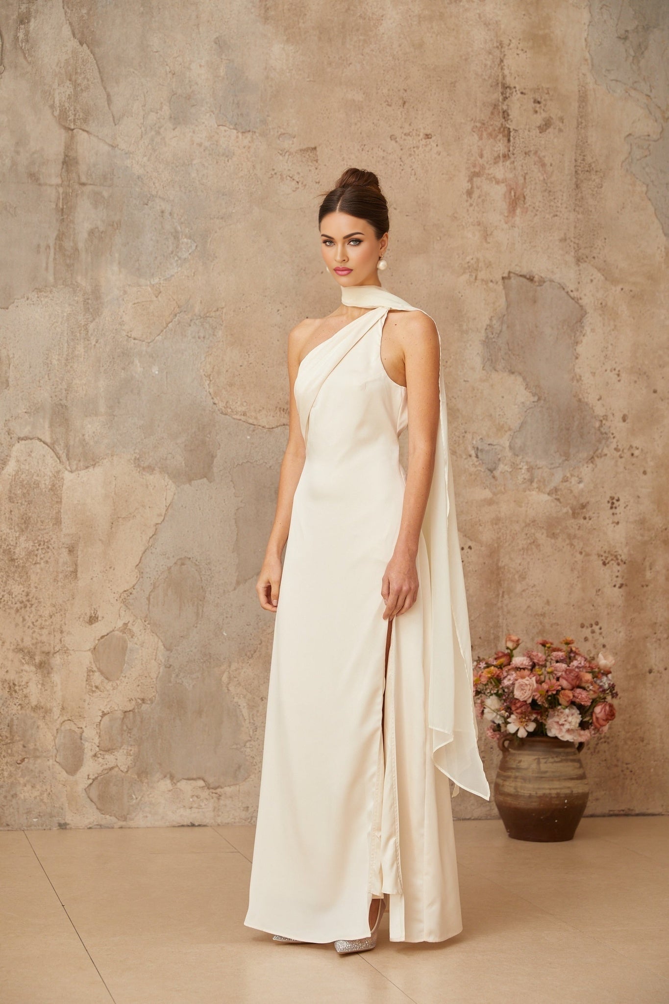 A long white satin maxi dress with a scarflike design detail featuring flowing fabric and an elegant drape