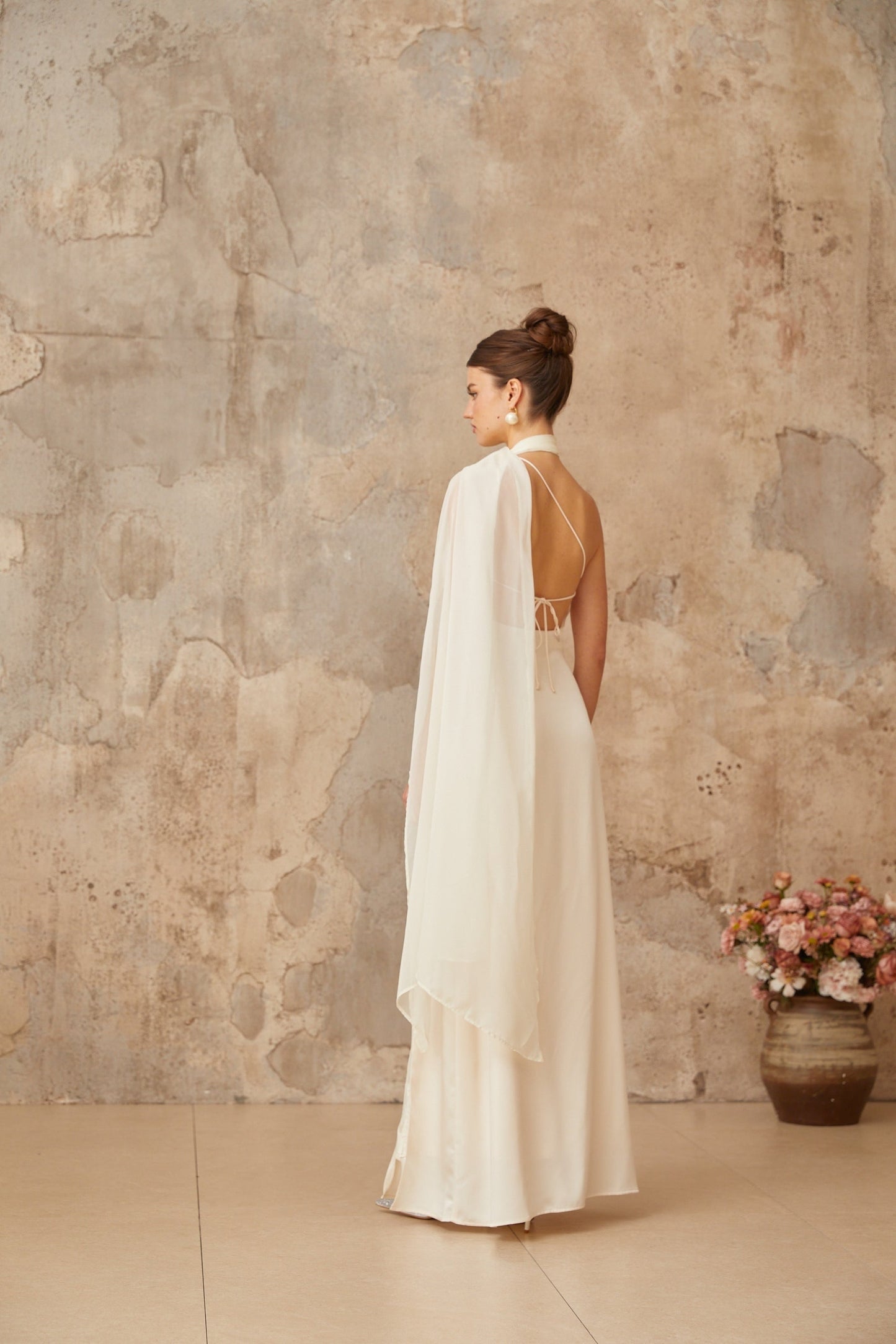 A long white satin maxi dress with a scarflike design featuring flowing fabric and elegant draping