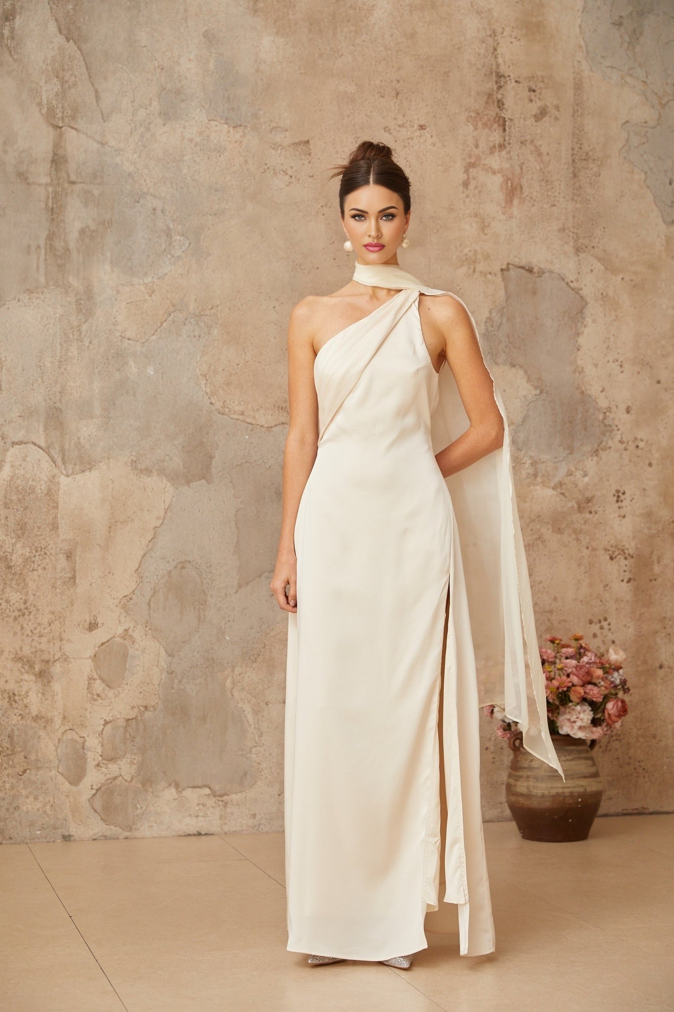 A long white satin maxi dress with a scarflike design featuring flowing fabric and elegant draping
