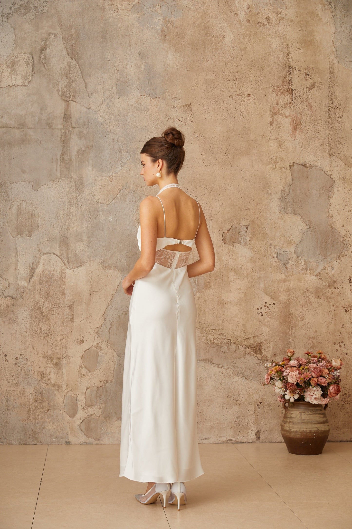 A long white satin maxi dress with lace panel details and a flowing silhouette
